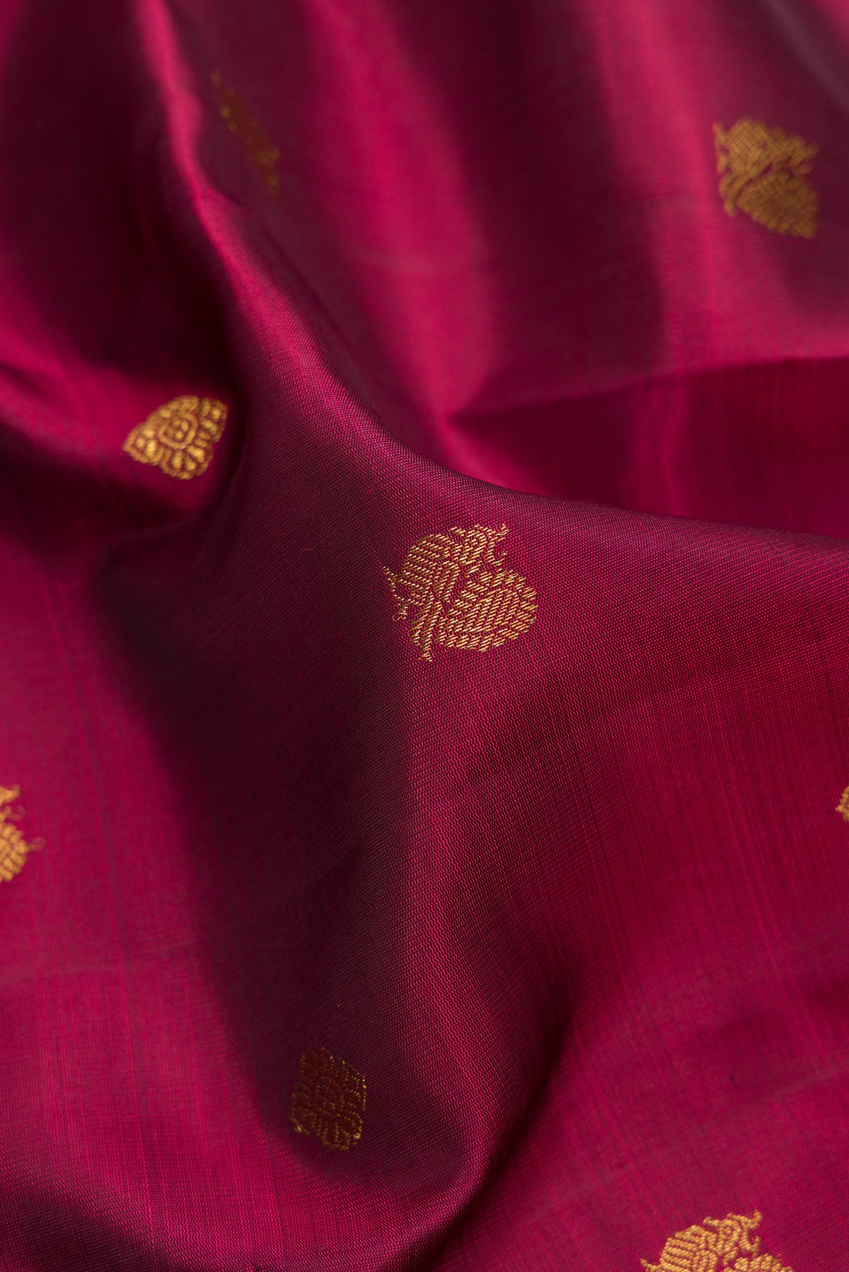 Close up of Pure Silk Pure Zari Maroon Dual Tone Kanjivaram Saree with Zari Butta on the body and Zari Border.  displaying folds