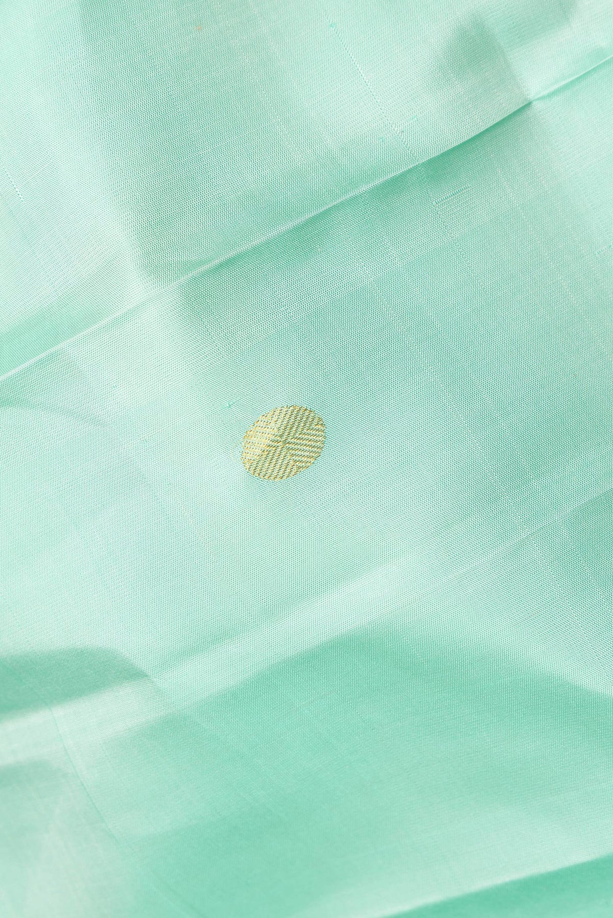 Close up of Pure Silk Pista Green Kanchipuram Saree with Zari Butta on the body and Zari And Thread Border.  displaying folds