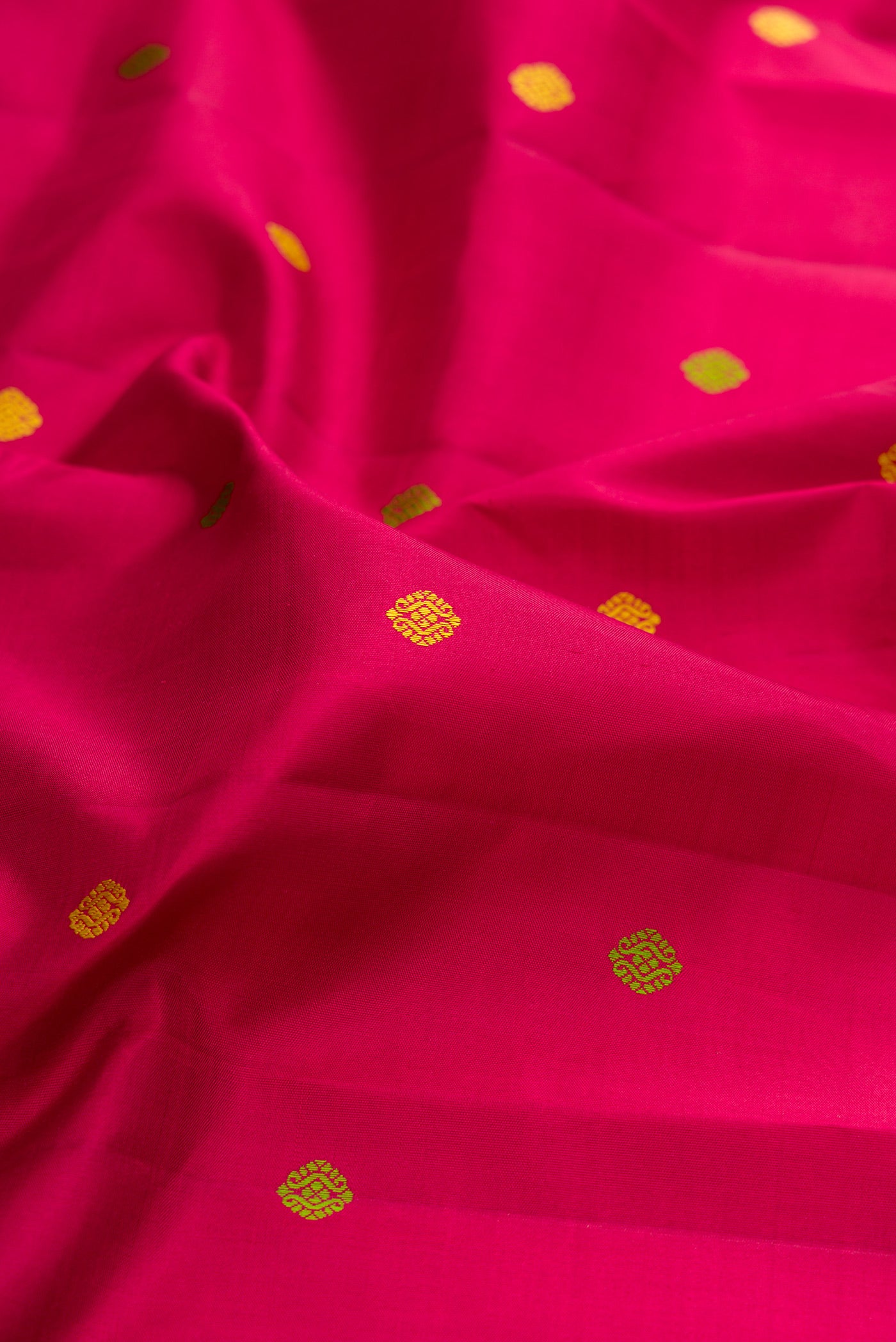Close up of Rani Pink Kanchipuram Silk Saree with Thread Butta on the body and Thread Border.  displaying folds