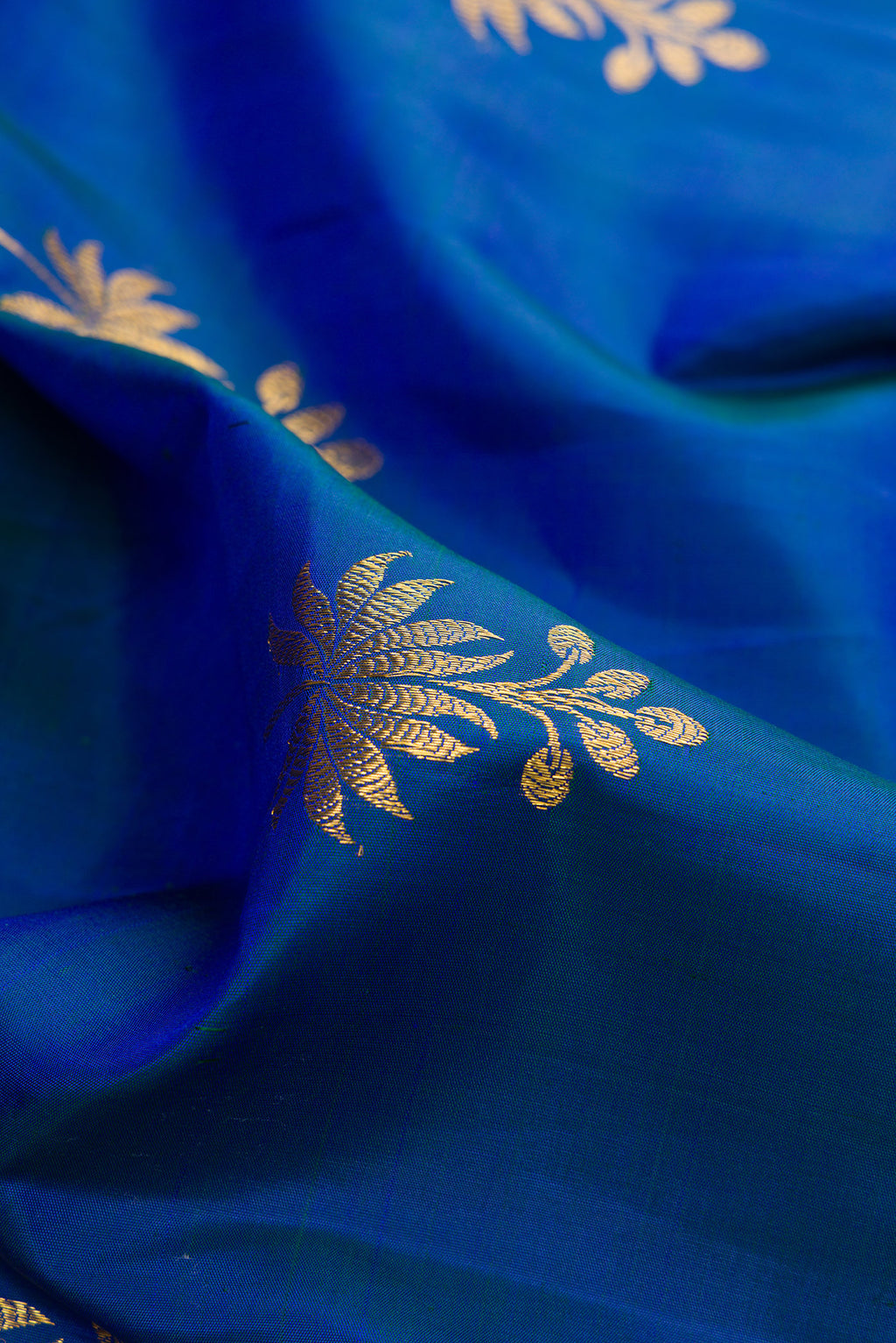 Close up of Pure Silk Blue Dual Tone Kanjivaram Saree with Zari Butta on the body and Zari Border.  displaying folds