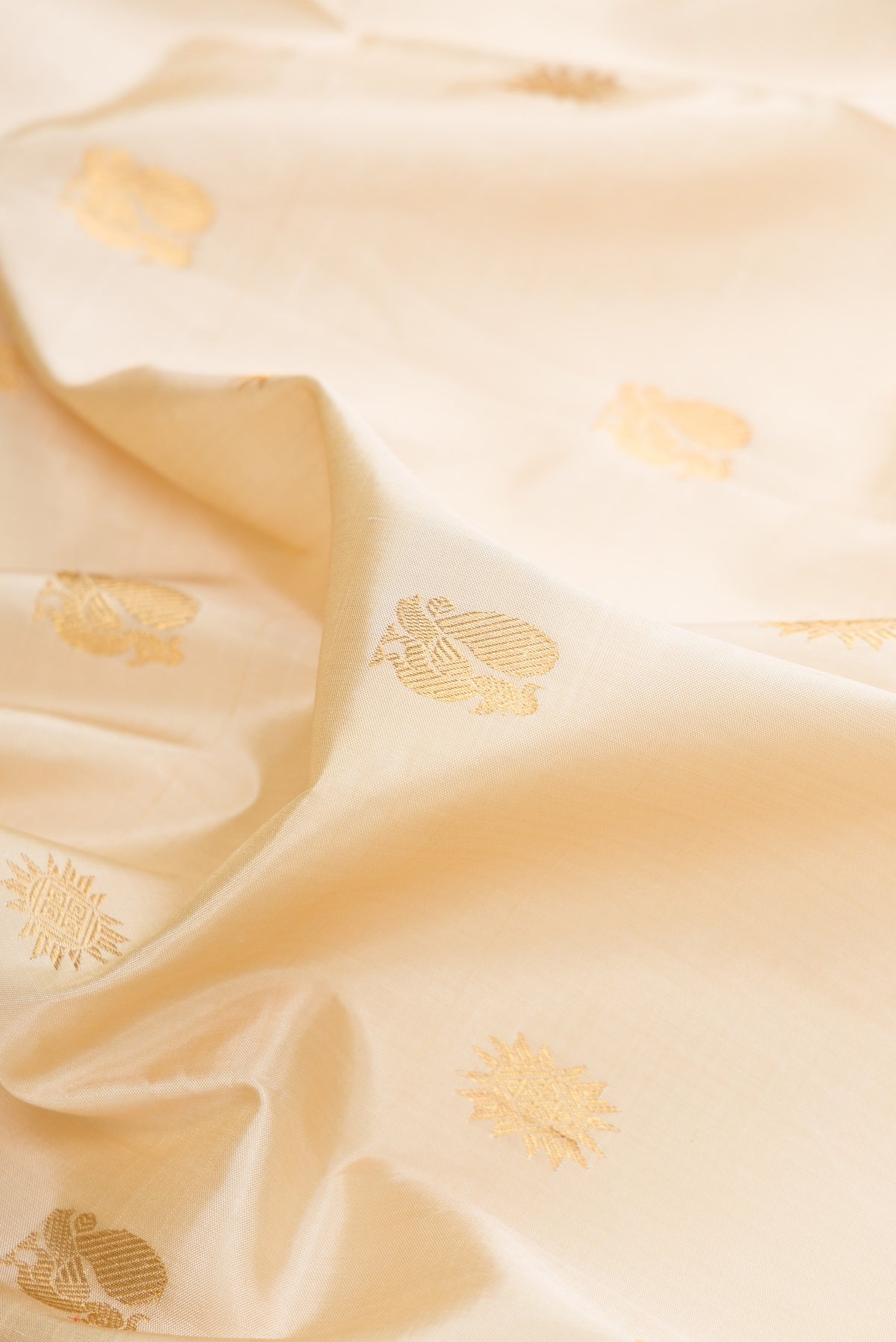 Close up of Pure Silk Beige Kanjivaram Saree with Zari Butta on the body and Zari Border.  displaying folds