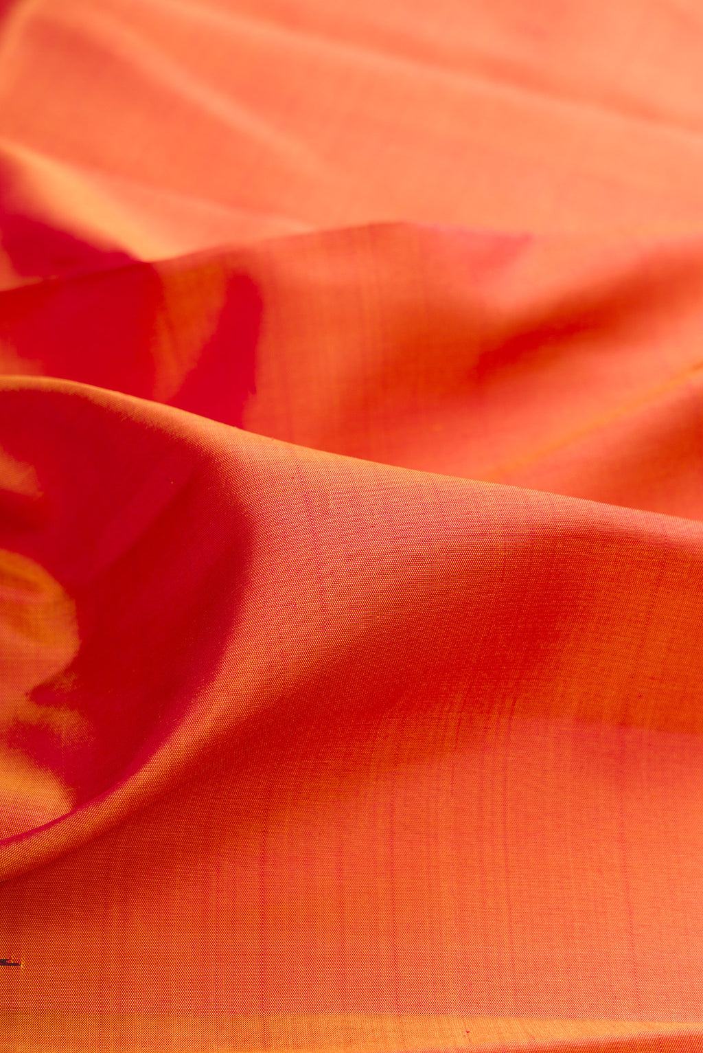 Close up of Pure Silk Brick Orange Dual Tone Kanchipuram Saree with Plain Body and Temple Border.  displaying folds