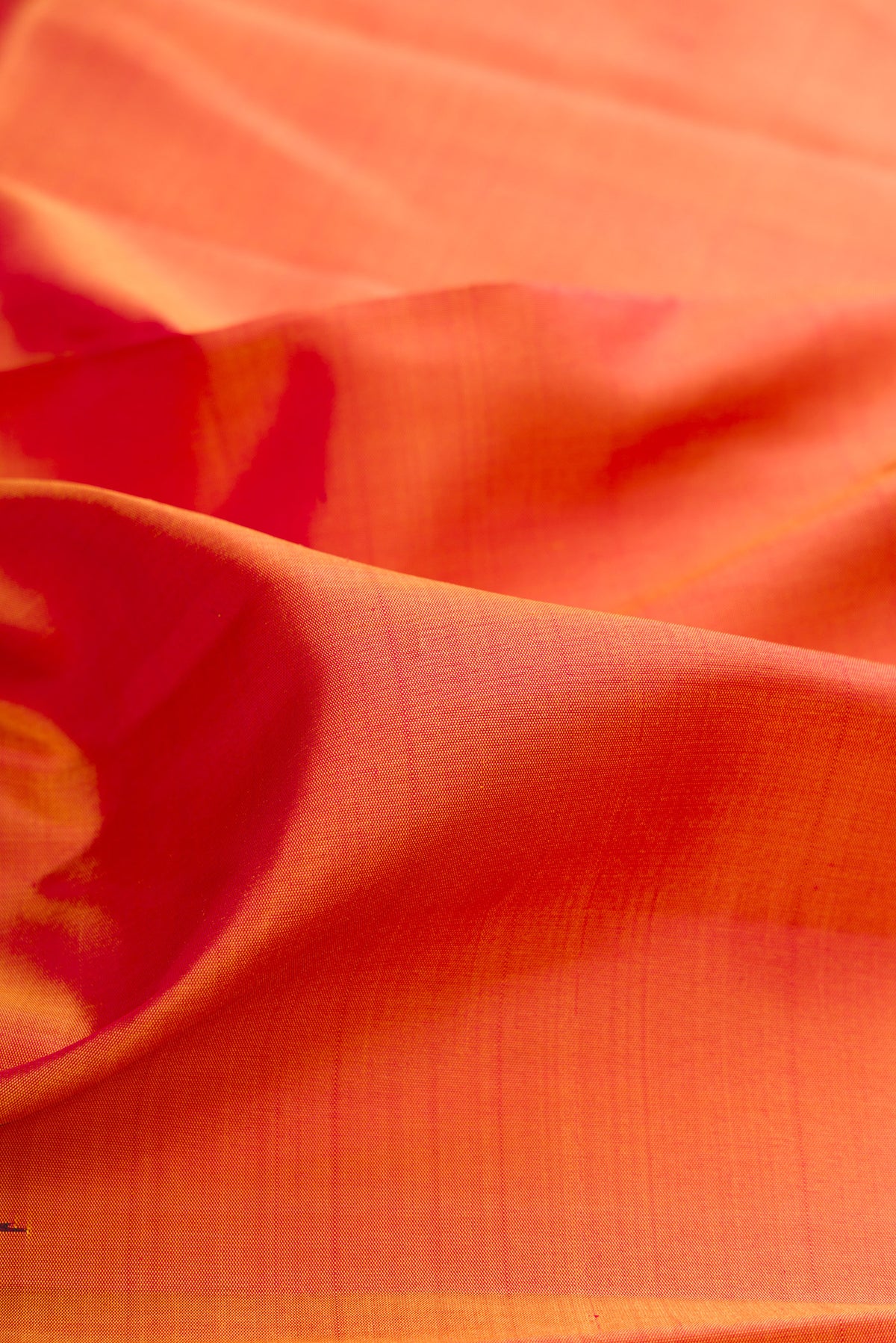 Close up of Pure Silk Brick Orange Dual Tone Kanchipuram Saree with Plain Body and Temple Border.  displaying folds