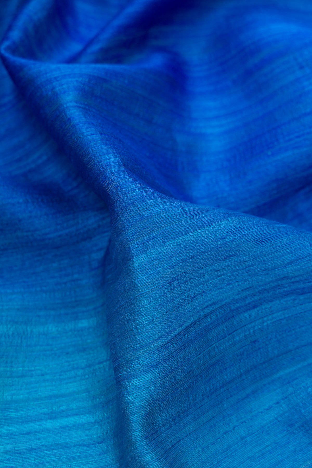 Close up of Pure Silk Royal Blue and Sea Green Color Tussar Saree with Ombre design on the body and Without Border.  displaying folds