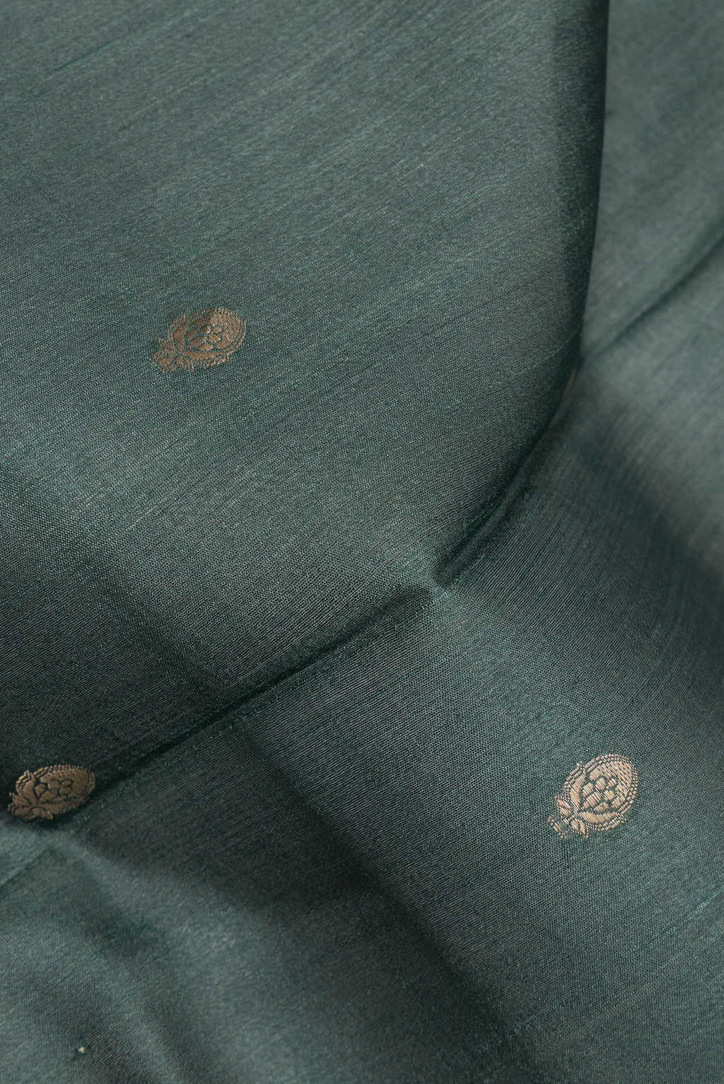 Close up of Bottle Green Tussar Saree with Zari Butta on the body and Fancy Border.  displaying folds