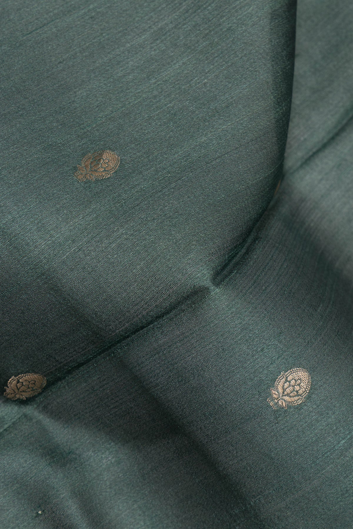 Close up of Bottle Green Tussar Saree with Zari Butta on the body and Fancy Border.  displaying folds