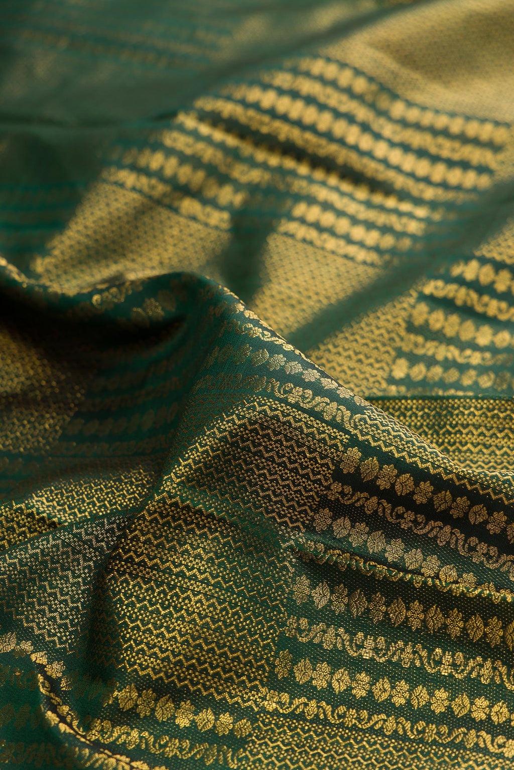 Close up of Pure Silk Bottle Green Kanchipuram Saree with Zari Brocade on the body and Zari Border.  displaying folds
