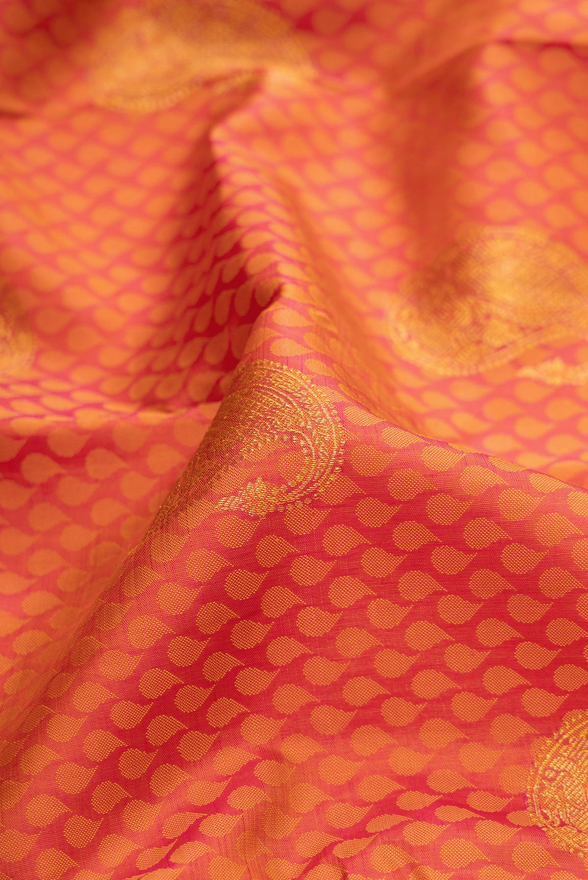Close up of Pure Silk Orange Dual Tone Kanchipuram Saree with Jacquard design on the body and Fancy Border.  displaying folds