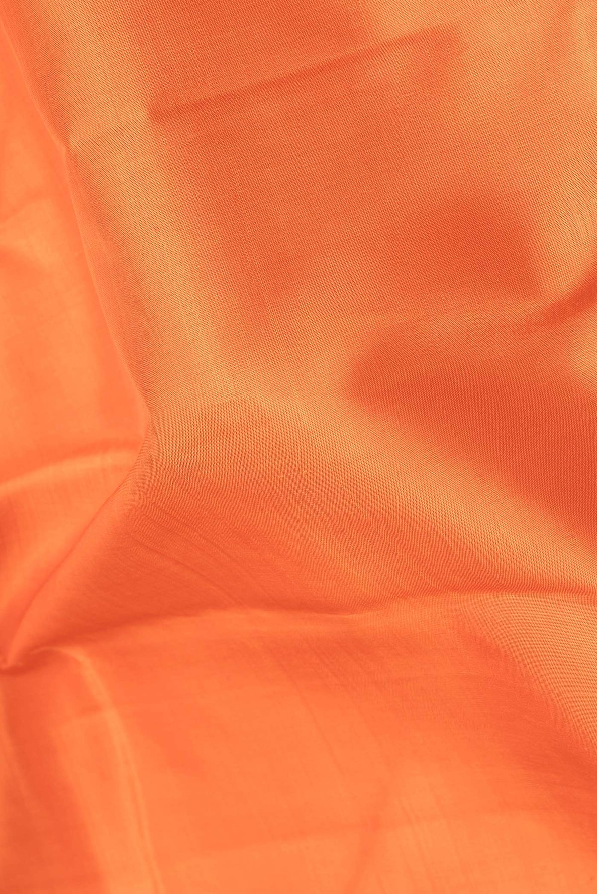 Close up of Pure Silk Orange Kanjivaram Saree with Plain Body and Zari Border.  displaying folds