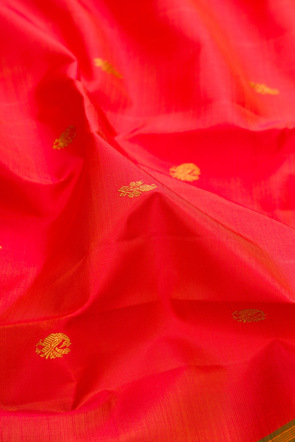 Close up of Pure Silk Orange Kanjivaram Saree with Zari Butta on the body and Zari Border.  displaying folds