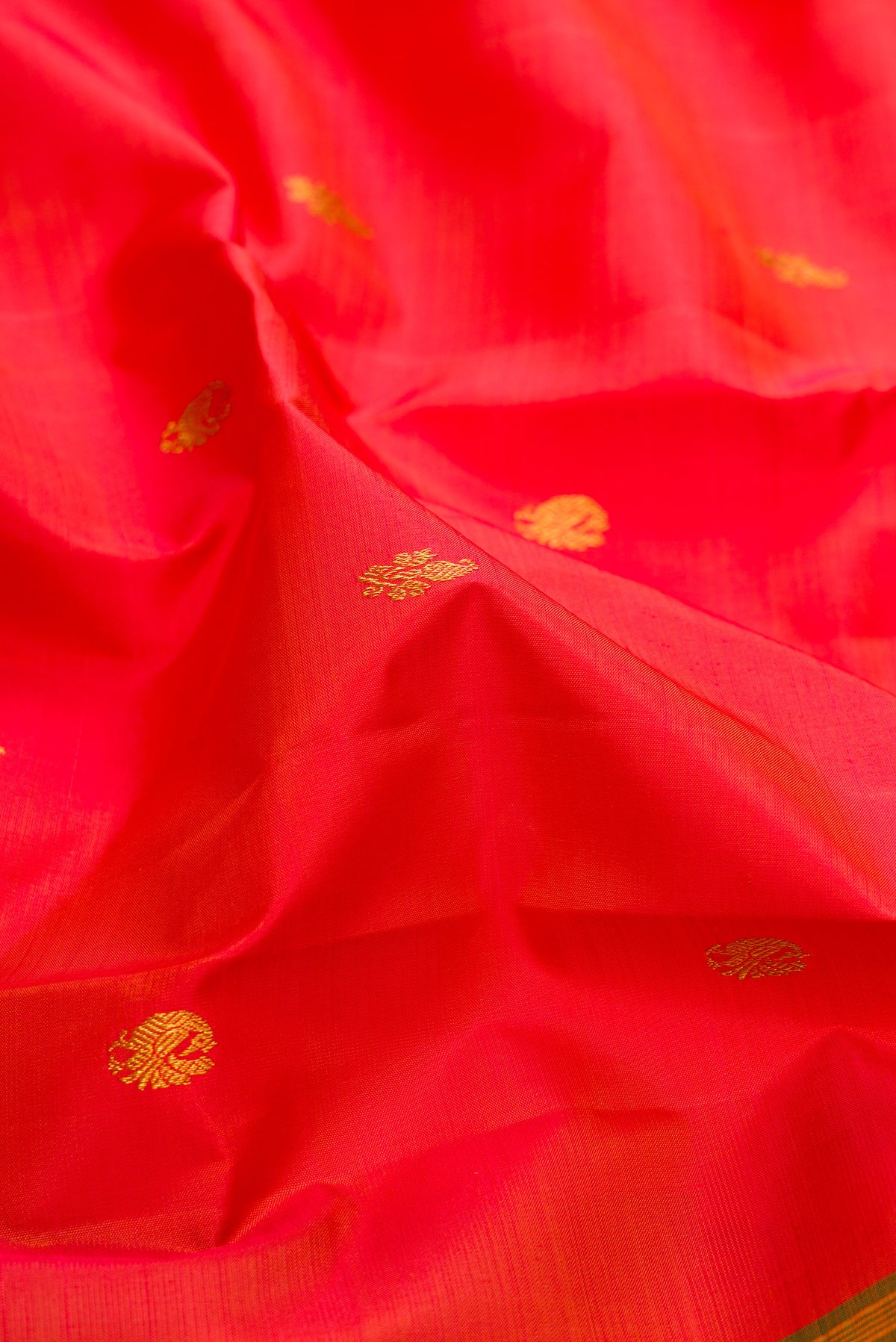 Close up of Pure Silk Orange Kanjivaram Saree with Zari Butta on the body and Zari Border.  displaying folds