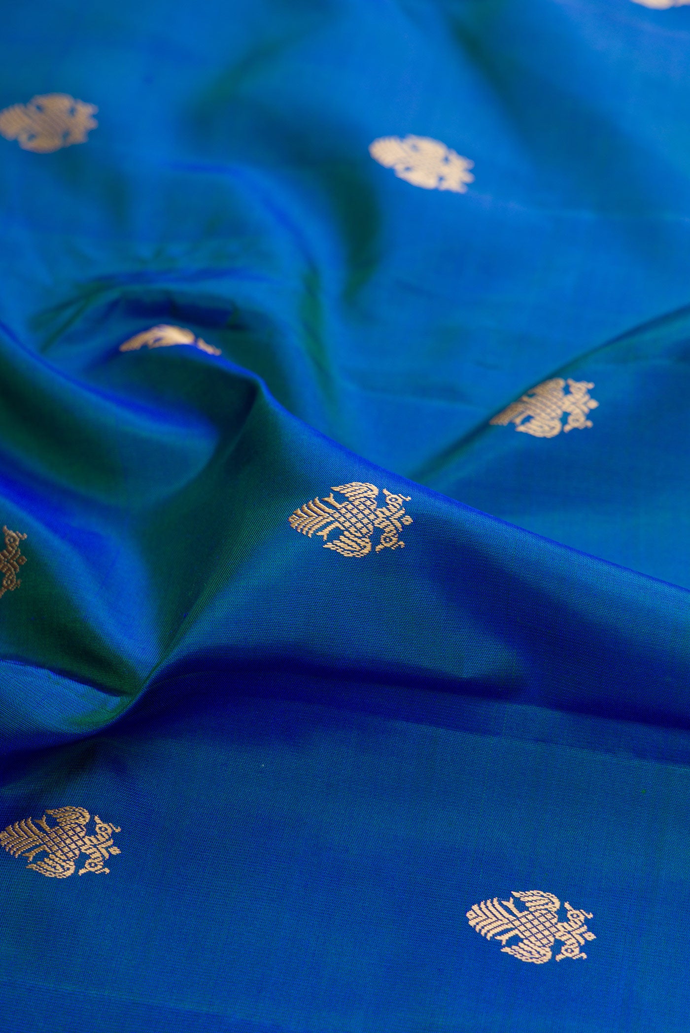 Close up of Peacock Blue Dual Tone Kanchipuram Silk Saree with Thread Butta on the body and Thread Border.  displaying folds