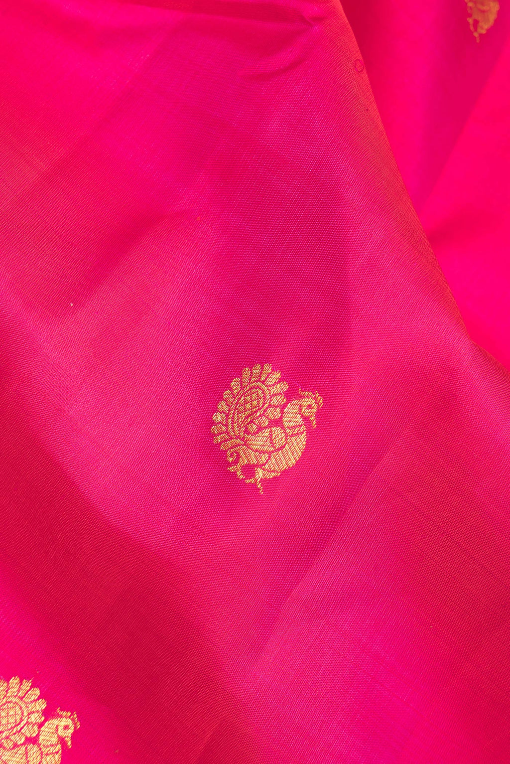 Close up of Pure Silk Dark Pink Kanjivaram Saree with Zari Butta on the body and Zari Border.  displaying folds