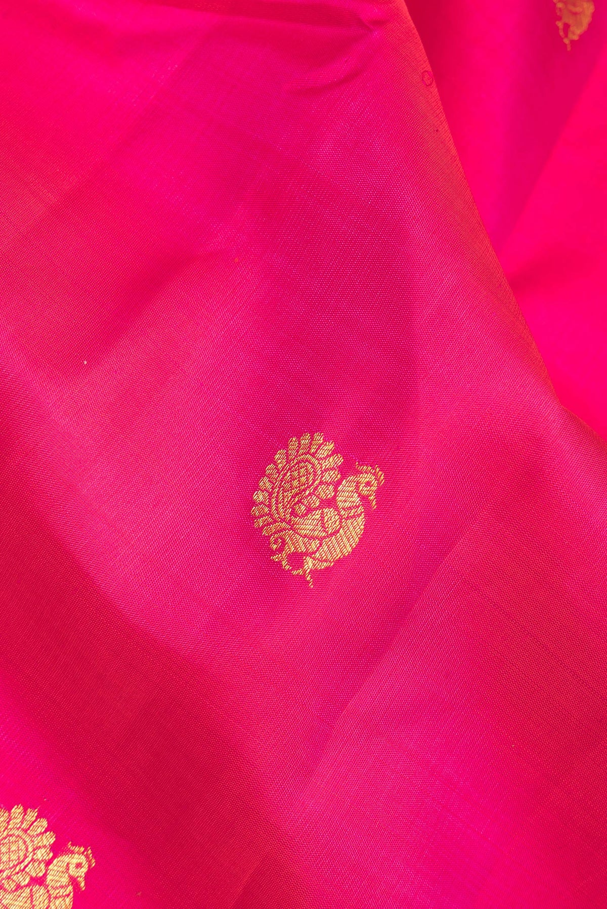 Close up of Pure Silk Dark Pink Kanjivaram Saree with Zari Butta on the body and Zari Border.  displaying folds
