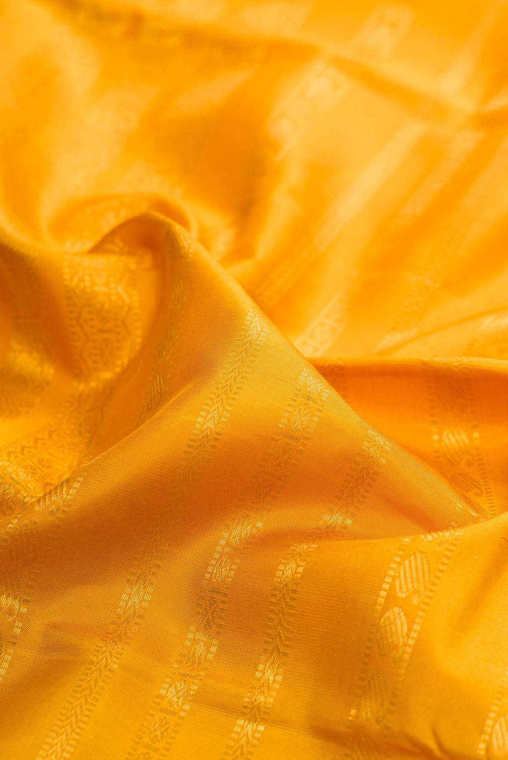 Close up of Mustard Kanchipuram Silk Saree with Stripes on the body and Ganga Jamuna Border.  displaying folds