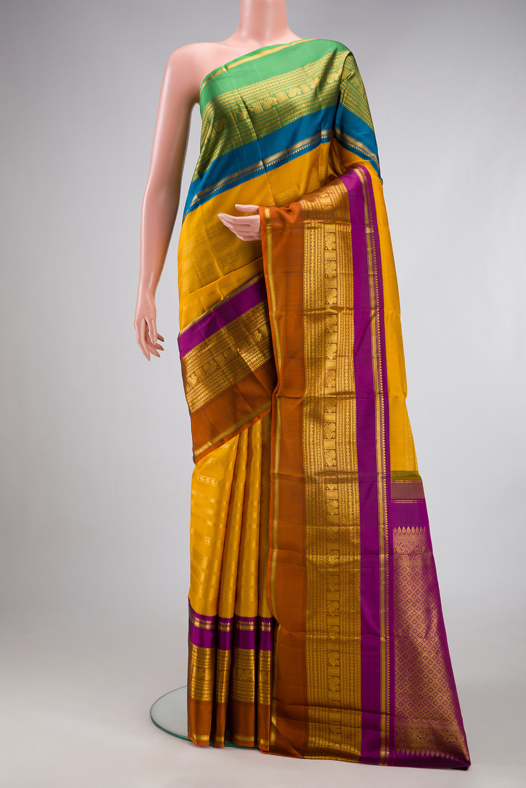 Mustard Kanchipuram Silk Saree with Stripes on the body and Ganga Jamuna Border.  displayed on a mannequin