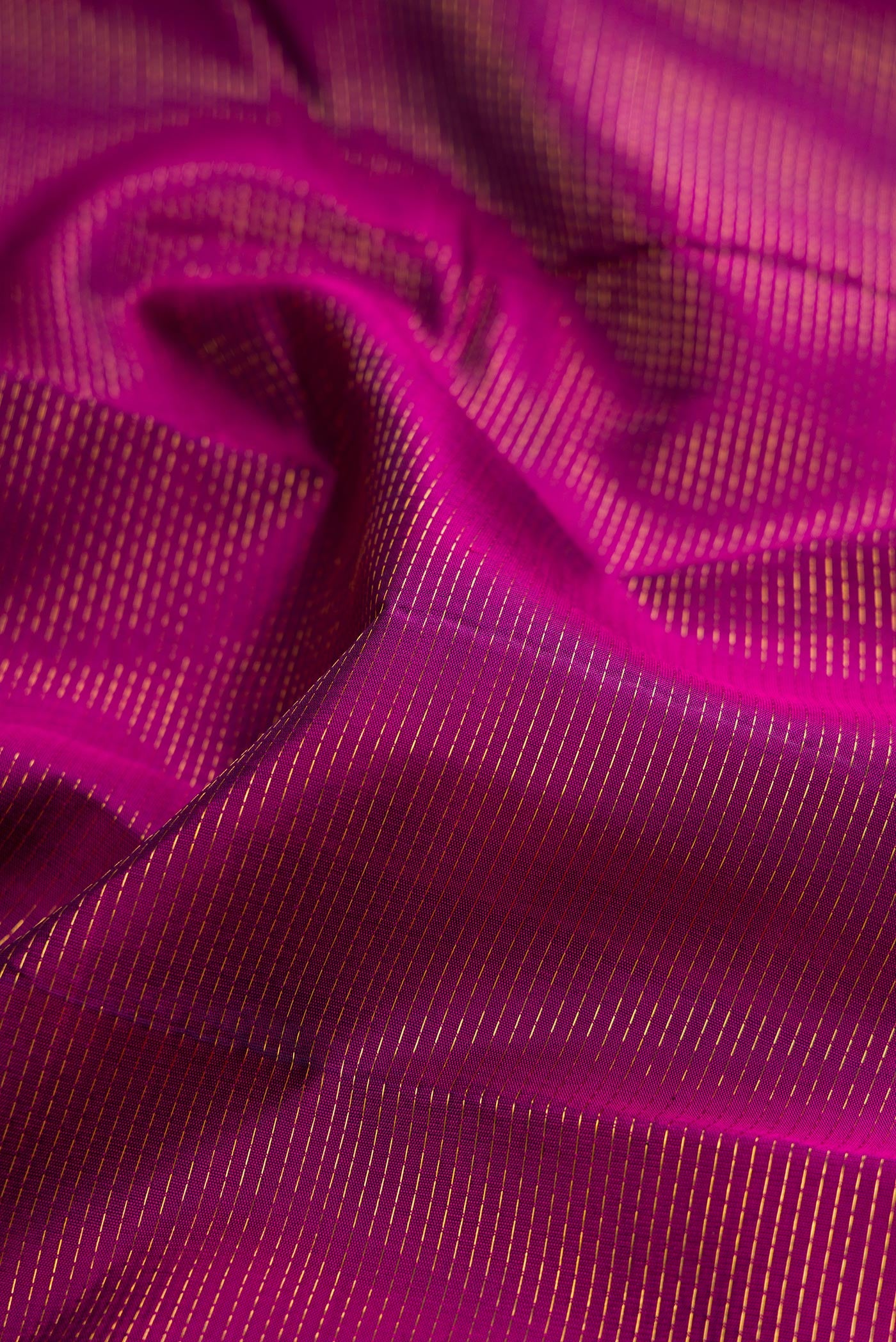 Close up of Magenta Kanjivaram Silk Saree with Stripes on the body and Ganga Jamuna Border.  displaying folds