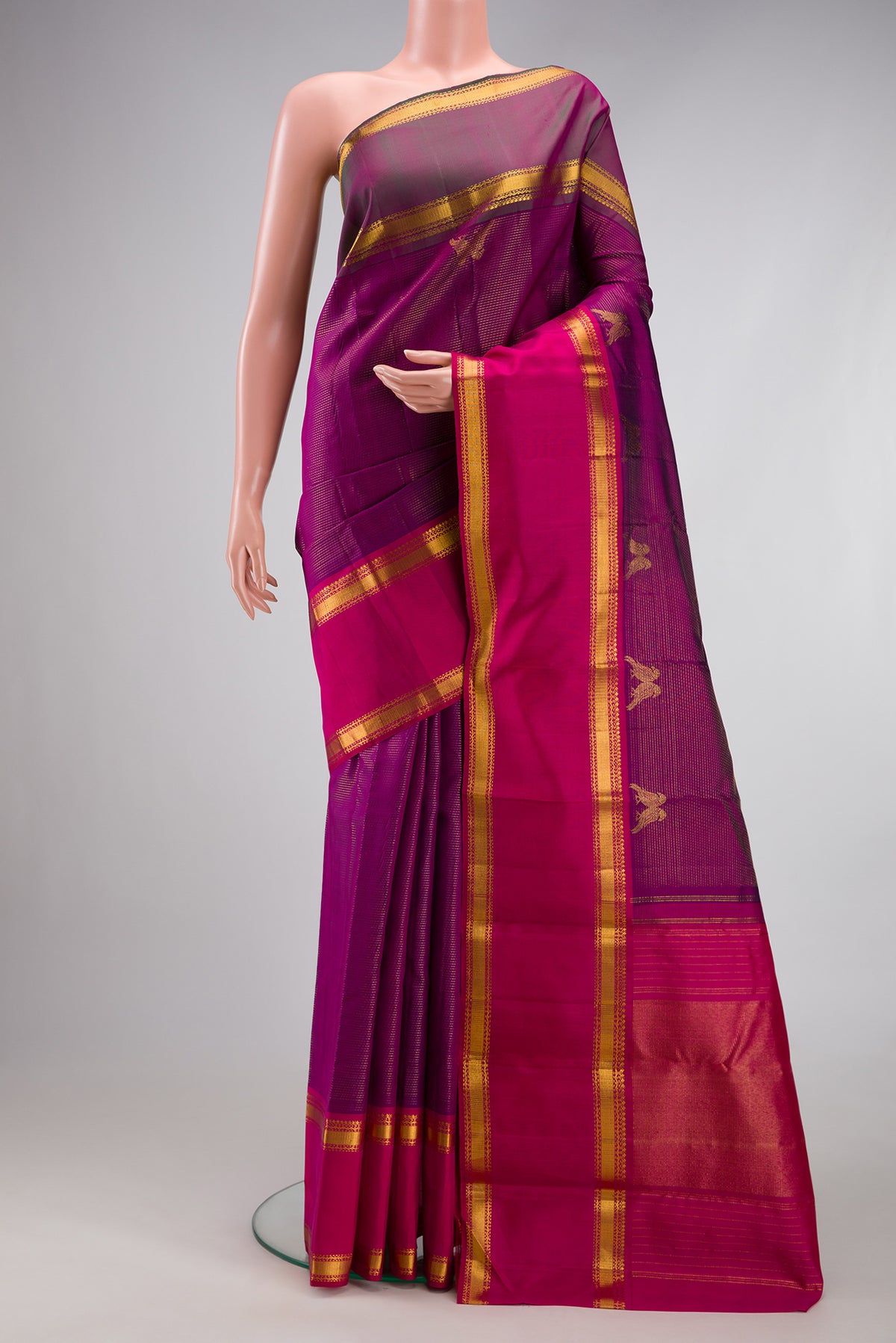 Magenta Kanjivaram Silk Saree with Stripes on the body and Ganga Jamuna Border.  displayed on a mannequin