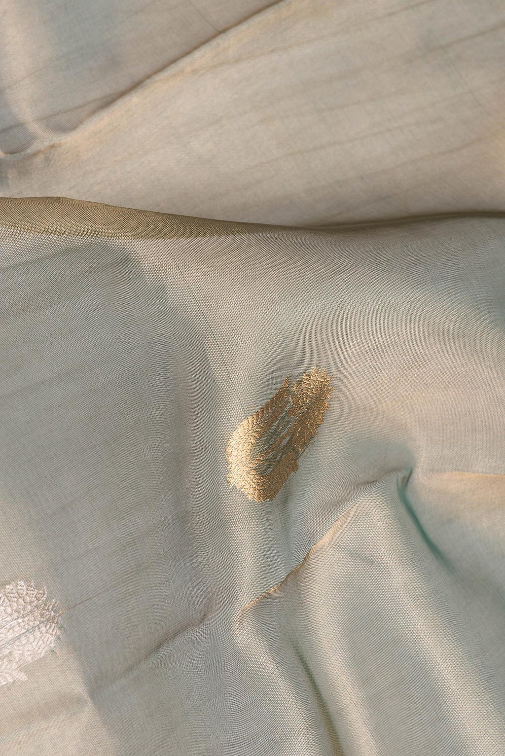 Close up of Green Dual Tone Organza Saree with Zari Butta on the body and Zari Border.  displaying folds