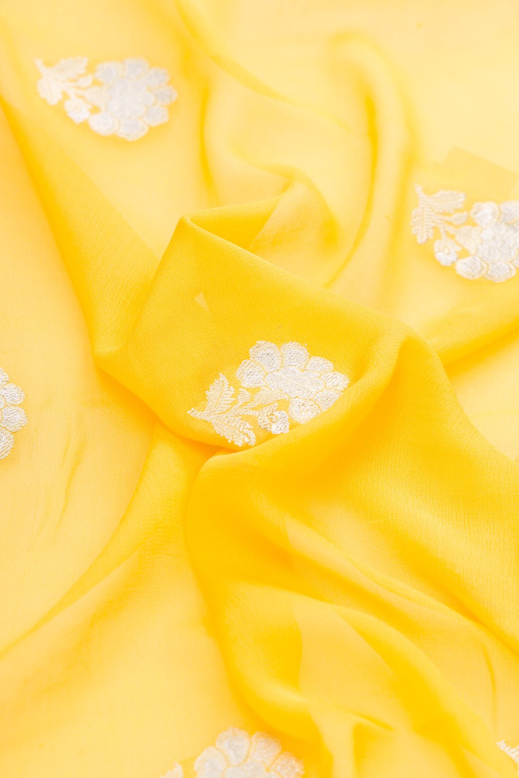 Close up of Yellow Banarasi Georgette Saree with Zari Butta on the body and Zari Border.  displaying folds