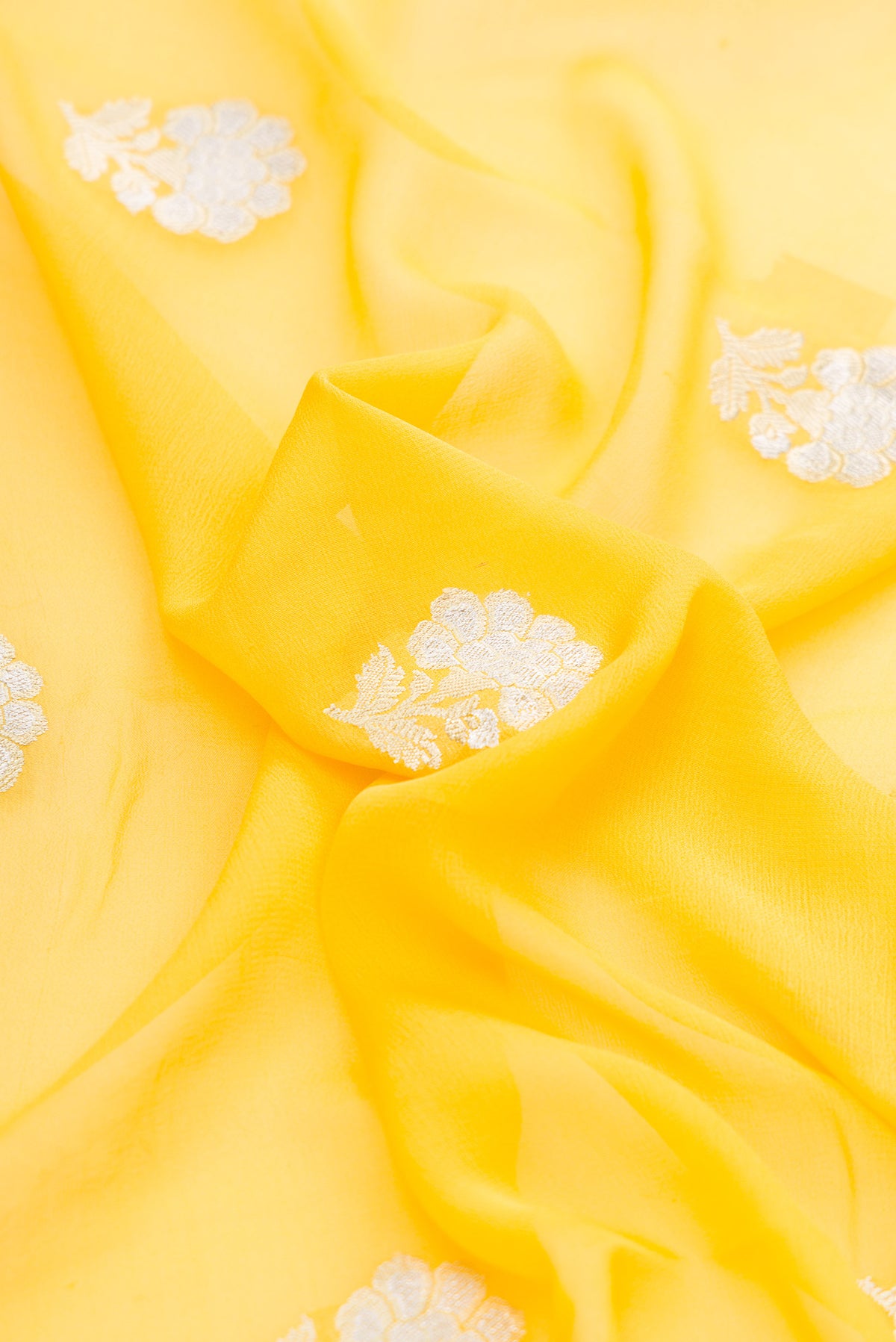 Close up of Yellow Banarasi Georgette Saree with Zari Butta on the body and Zari Border.  displaying folds