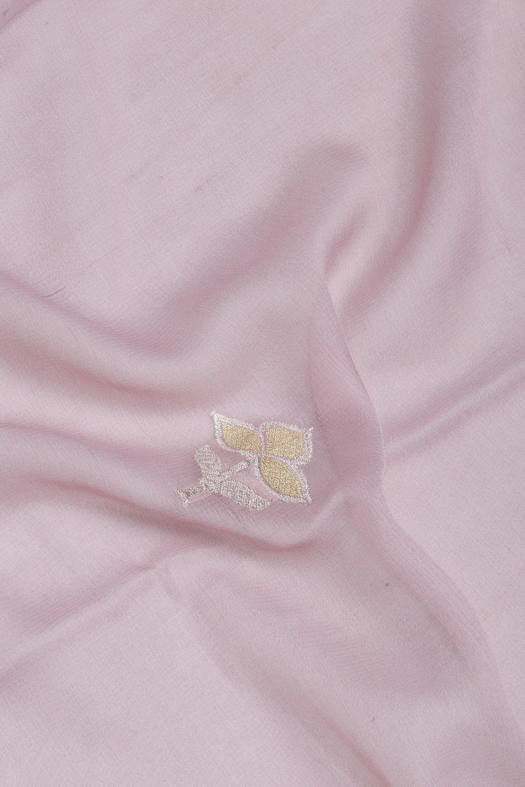 Close up of Rose Gold Banarasi Georgette Saree with Zari Butta on the body and Zari Border.  displaying folds