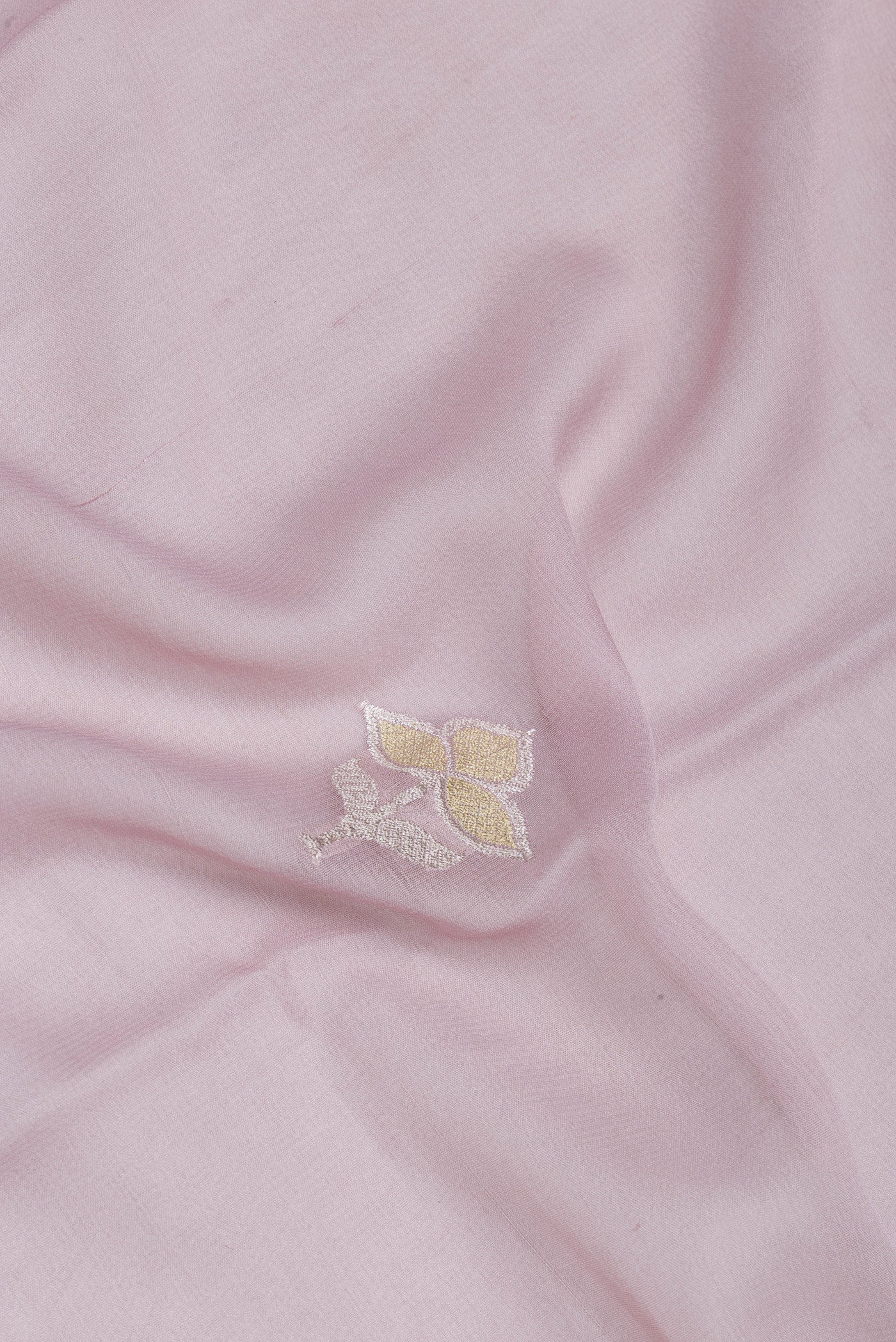 Close up of Rose Gold Banarasi Georgette Saree with Zari Butta on the body and Zari Border.  displaying folds