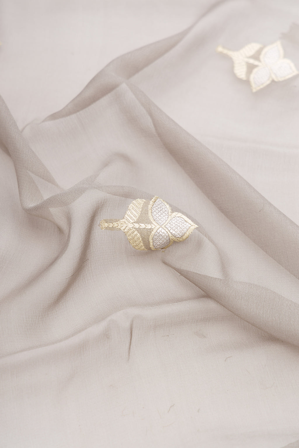 Close up of Grey Banarasi Georgette Saree with Zari Butta on the body and Zari Border.  displaying folds