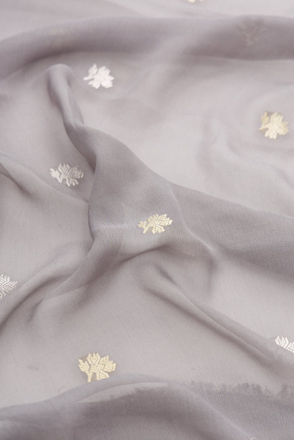Close up of Grey Banarasi Georgette Saree with Zari Butta on the body and Fancy Border.  displaying folds