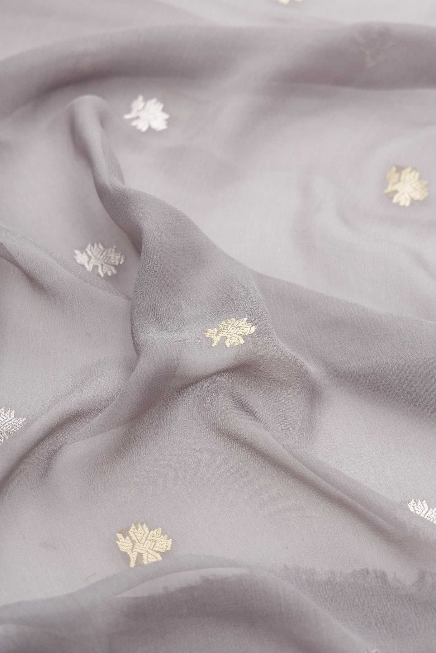 Close up of Grey Banarasi Georgette Saree with Zari Butta on the body and Fancy Border.  displaying folds