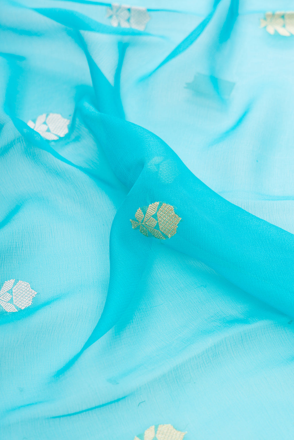 Close up of Sky Blue Banarasi Georgette Saree with Zari Butta on the body and Fancy Border.  displaying folds