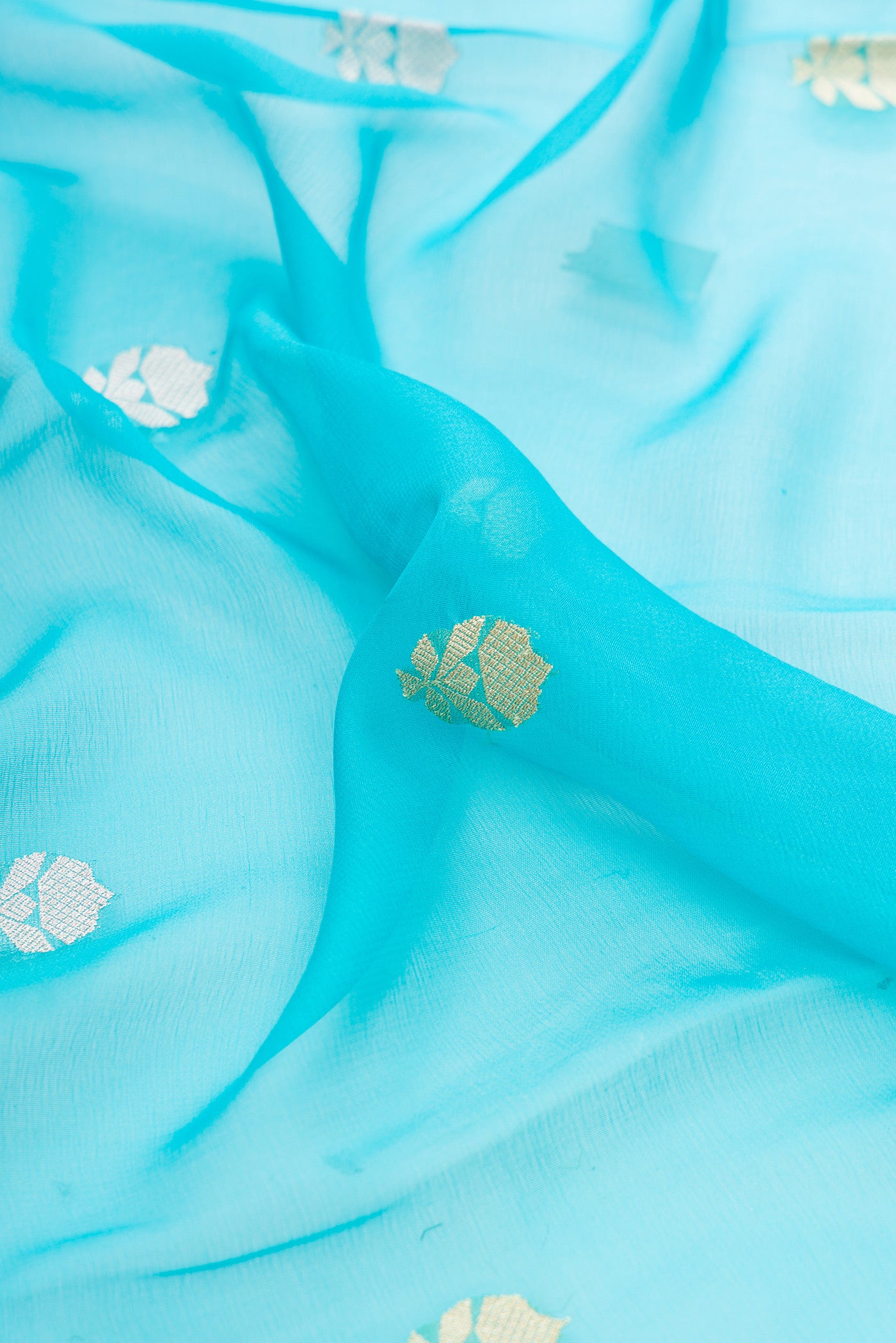 Close up of Sky Blue Banarasi Georgette Saree with Zari Butta on the body and Fancy Border.  displaying folds