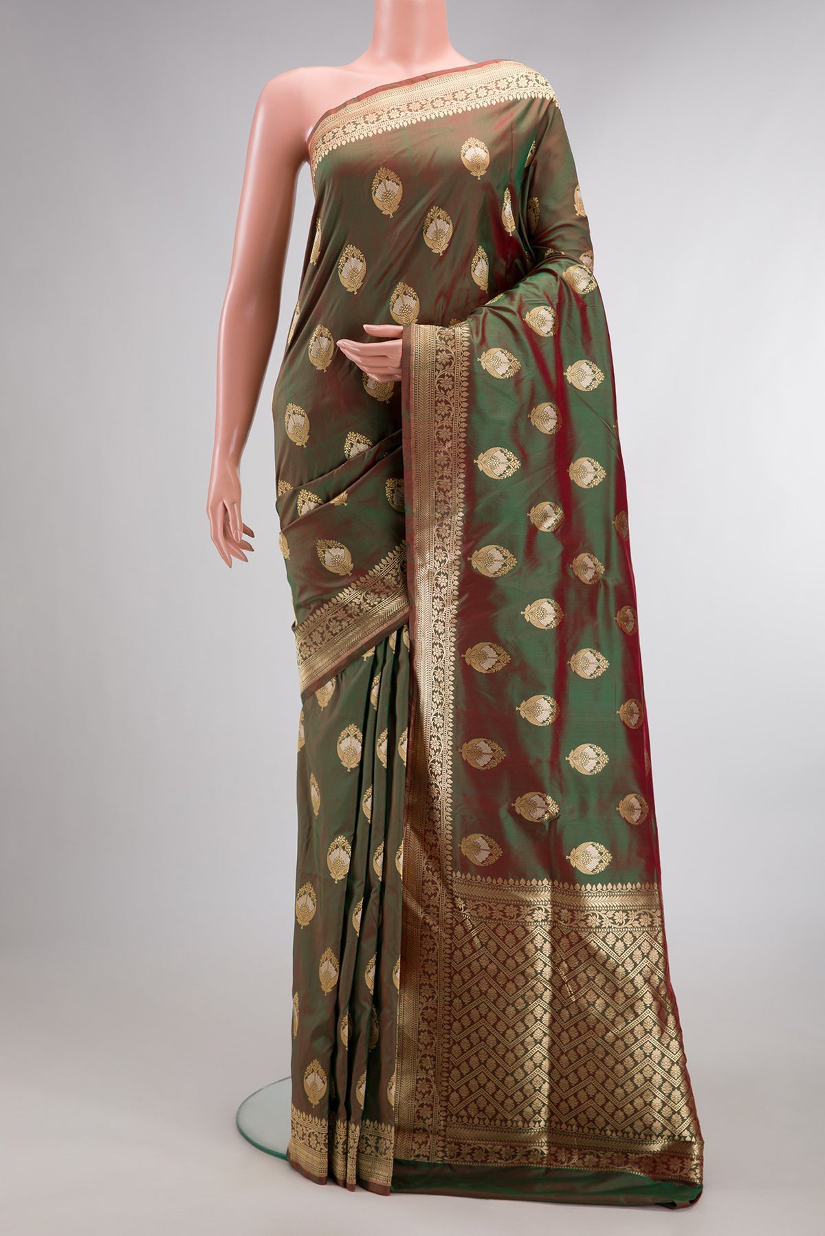 Pure Silk Mehandi Green Dual Tone Banarasi Saree with Zari And Thread Butta on the body and Fancy Border.  displayed on a mannequin