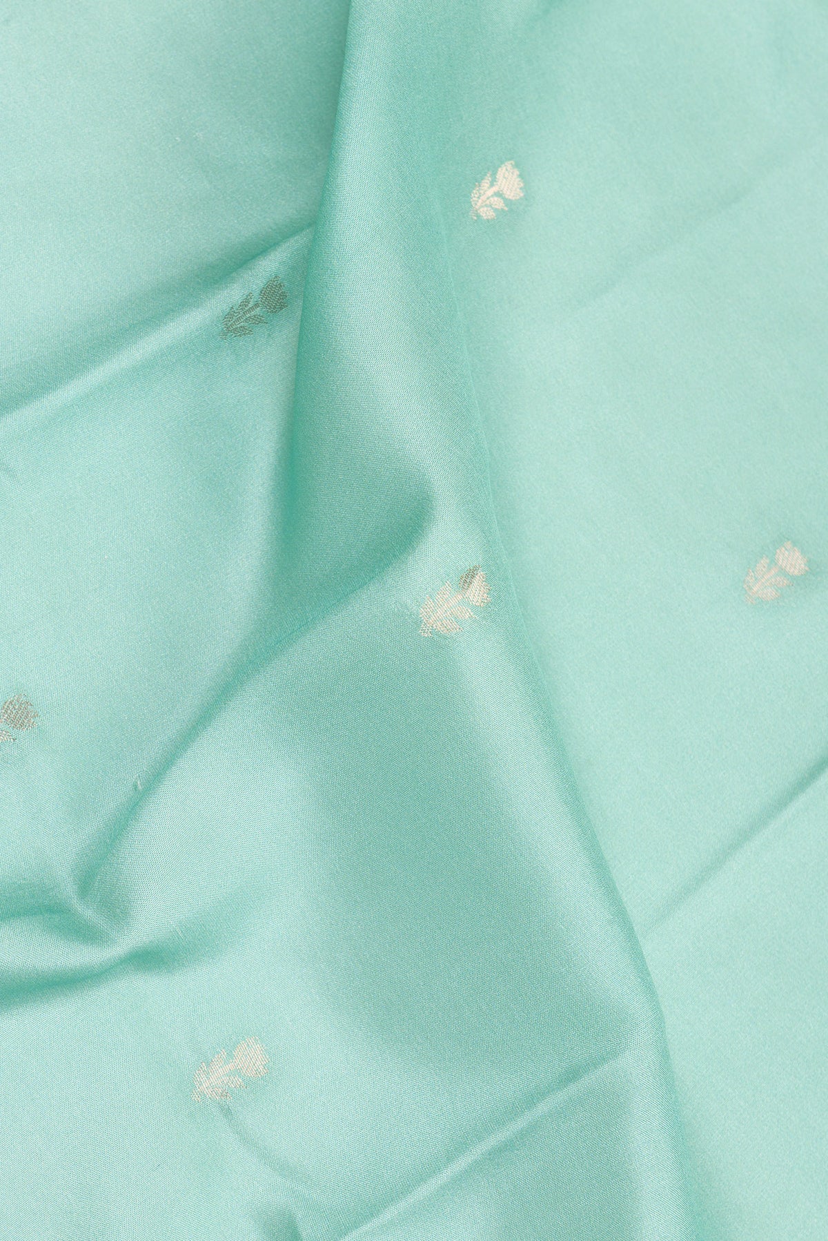 Close up of Light Green Dual Tone Crepe Saree with Zari Butta on the body and Fancy Border.  displaying folds
