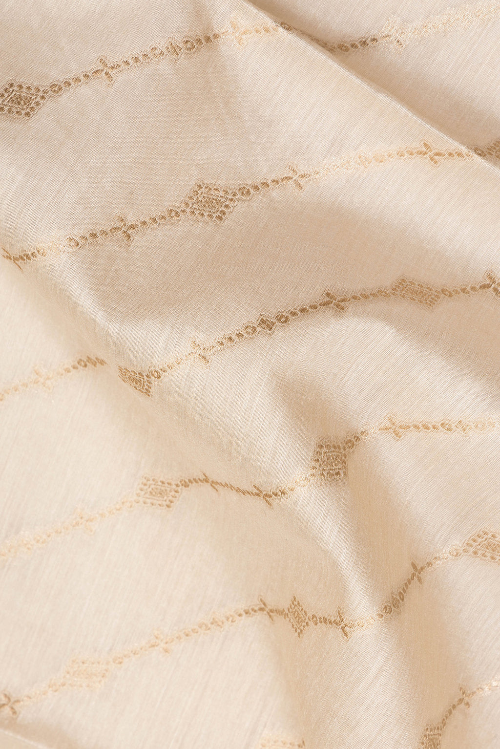 Close up of Beige Tussar Saree with Zari Butta on the body and Embroidered Border.  displaying folds