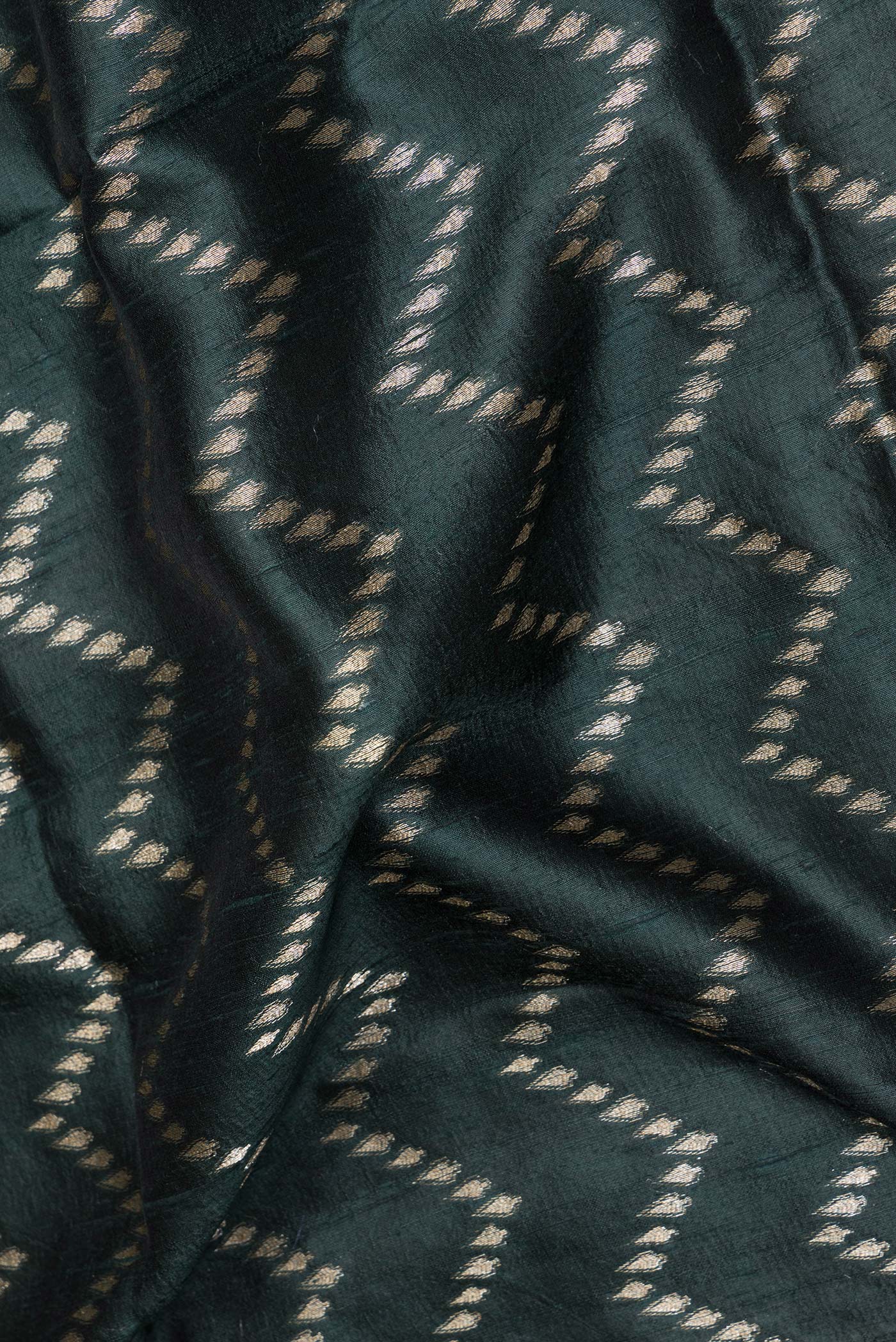Close up of Pure Silk Bottle Green Tussar Saree with Zig Zag design on the body and Zari Border.  displaying folds
