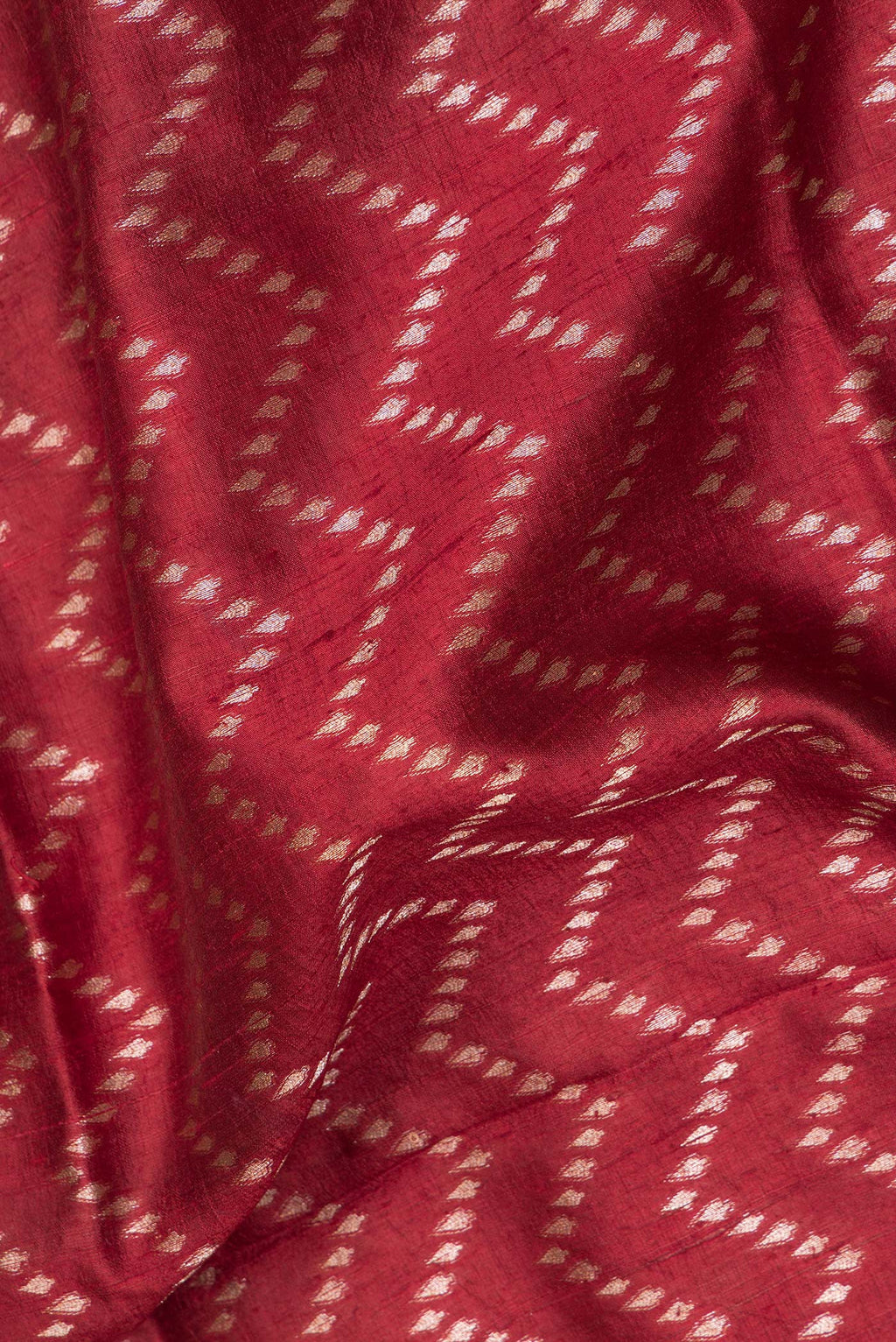 Close up of Pure Silk Maroon Tussar Saree with Zig Zag design on the body and Zari Border.  displaying folds
