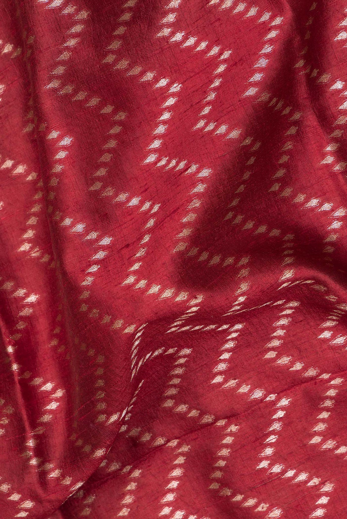 Close up of Pure Silk Maroon Tussar Saree with Zig Zag design on the body and Zari Border.  displaying folds