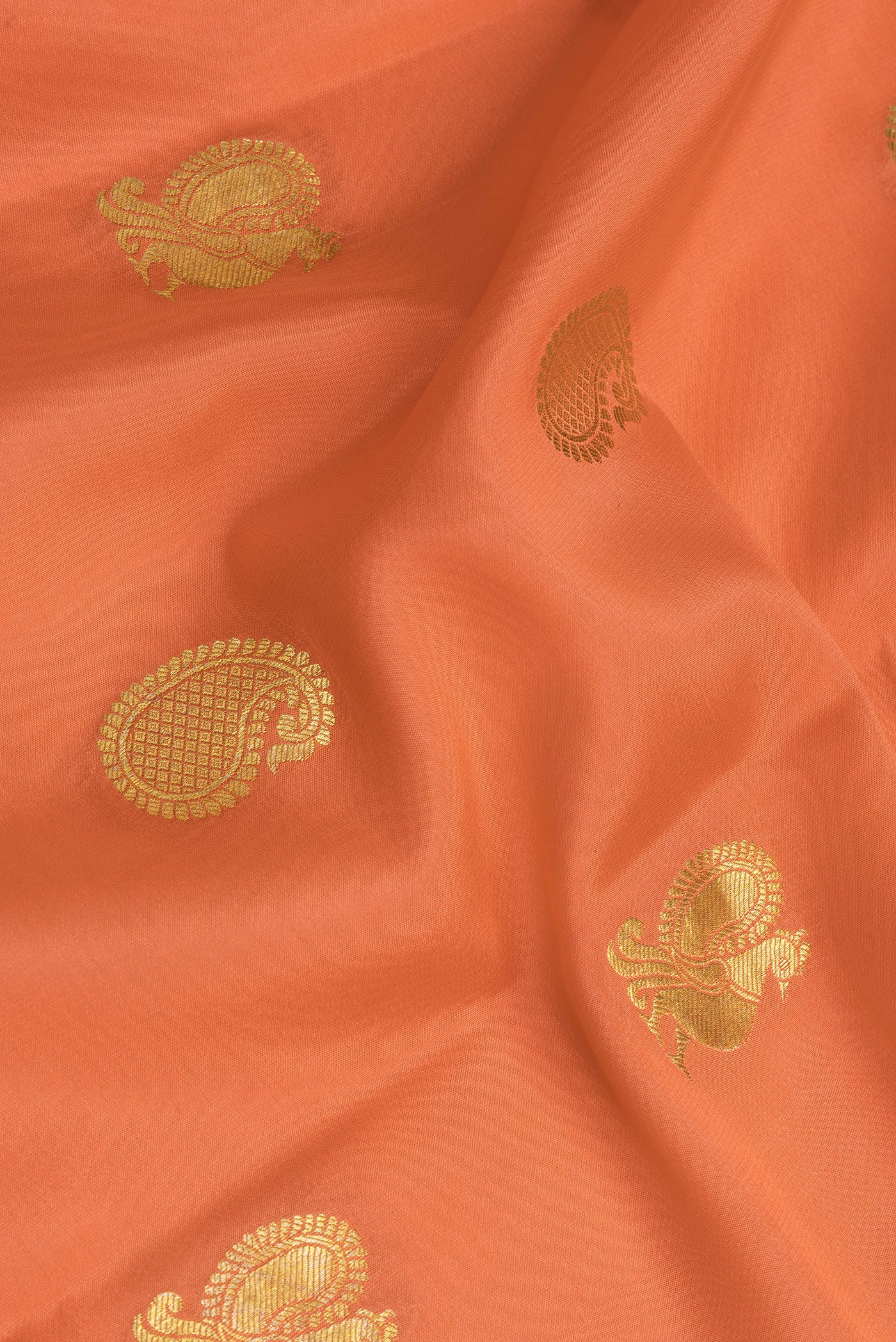 Close up of Golden Peach Mysore Crepe Saree with Zari Butta on the body and Fancy Border.  displaying folds