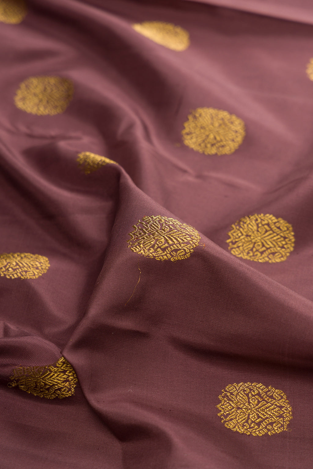 Close up of Pure Silk Pure Zari Brown Kanjivaram Saree with Zari Butta on the body and Zari Border.  displaying folds