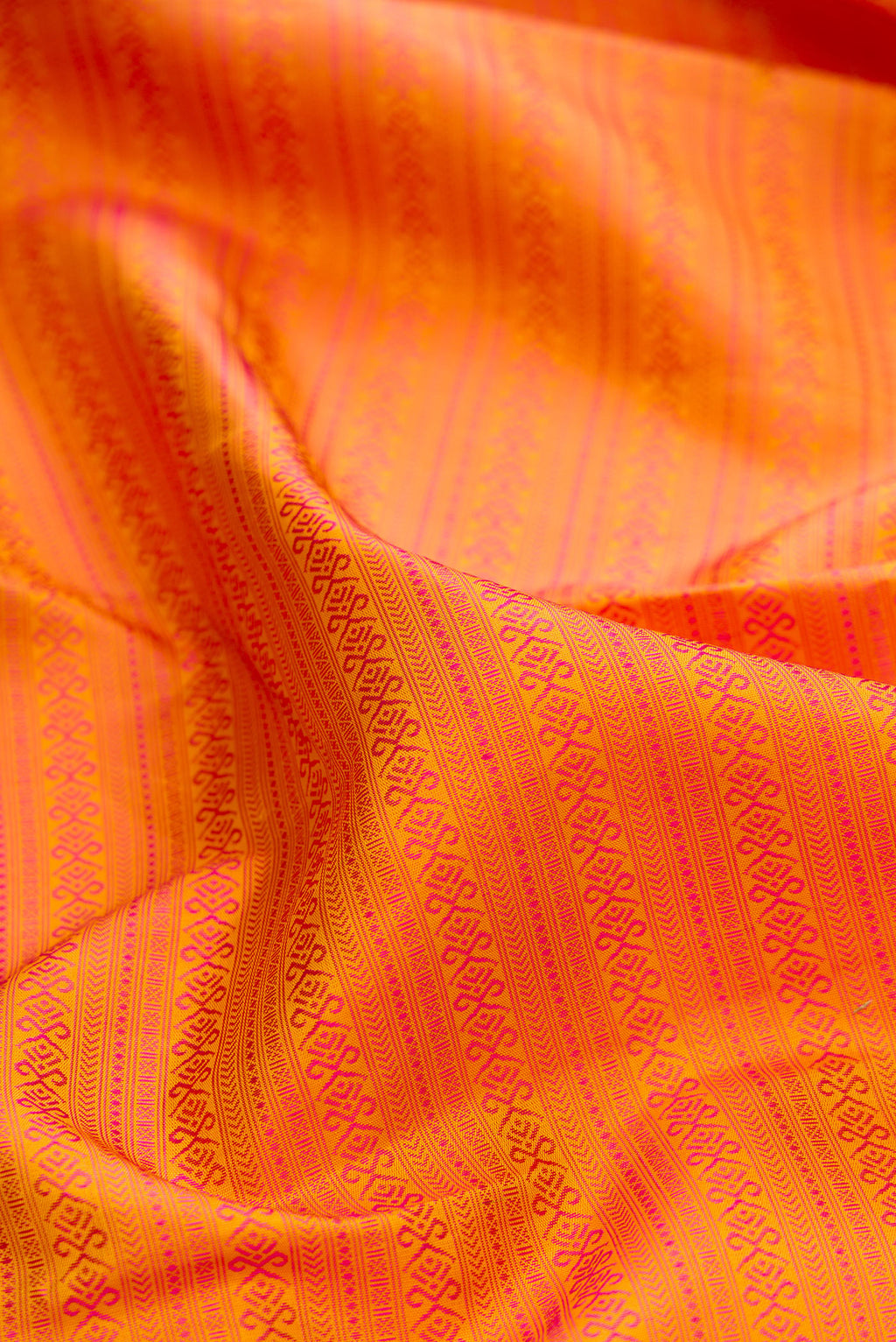 Close up of Pure Silk Pure Zari Orange Kanjivaram Saree with Jacquard design on the body and Zari And Thread Border.  displaying folds