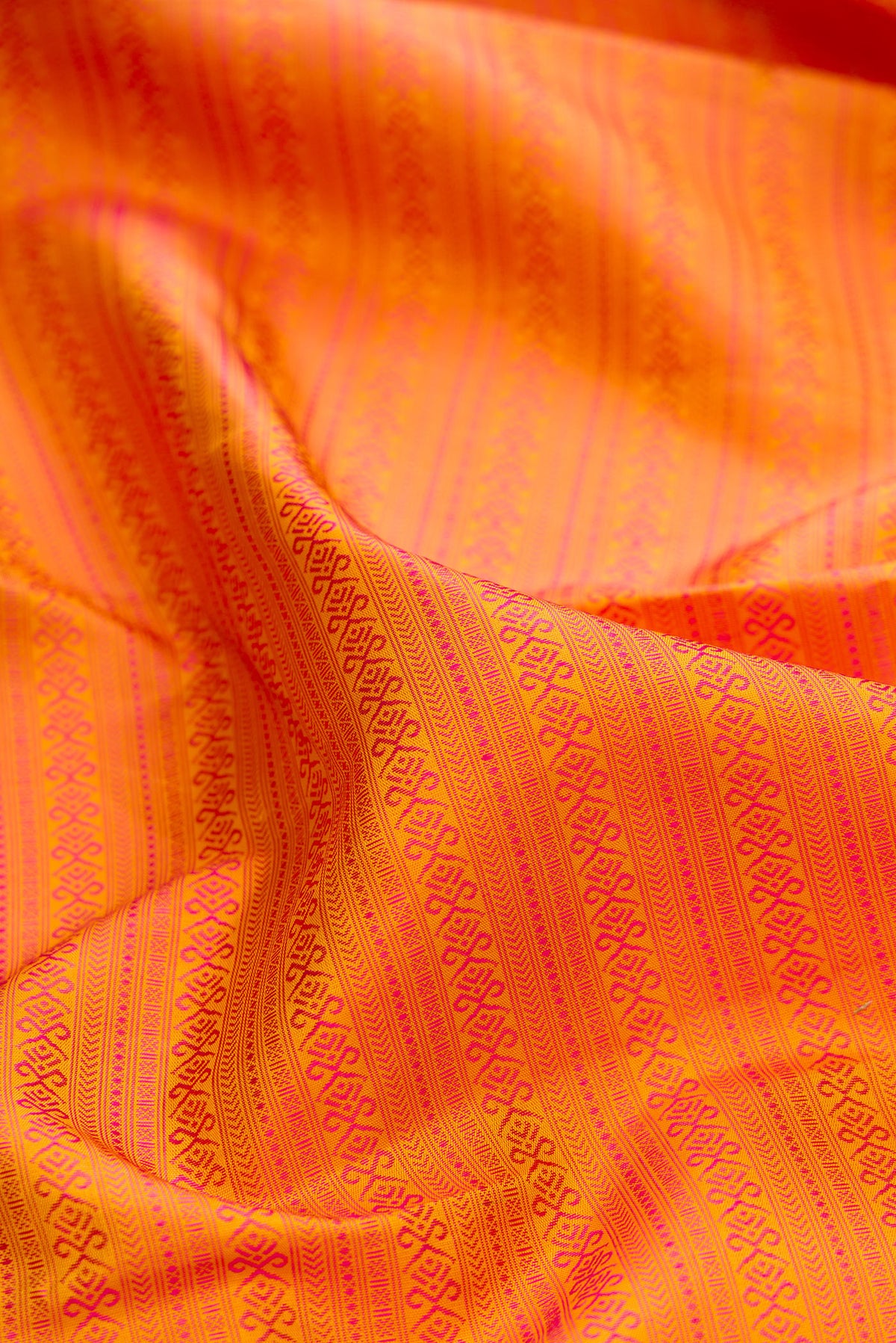 Close up of Pure Silk Pure Zari Orange Kanjivaram Saree with Jacquard design on the body and Zari And Thread Border.  displaying folds