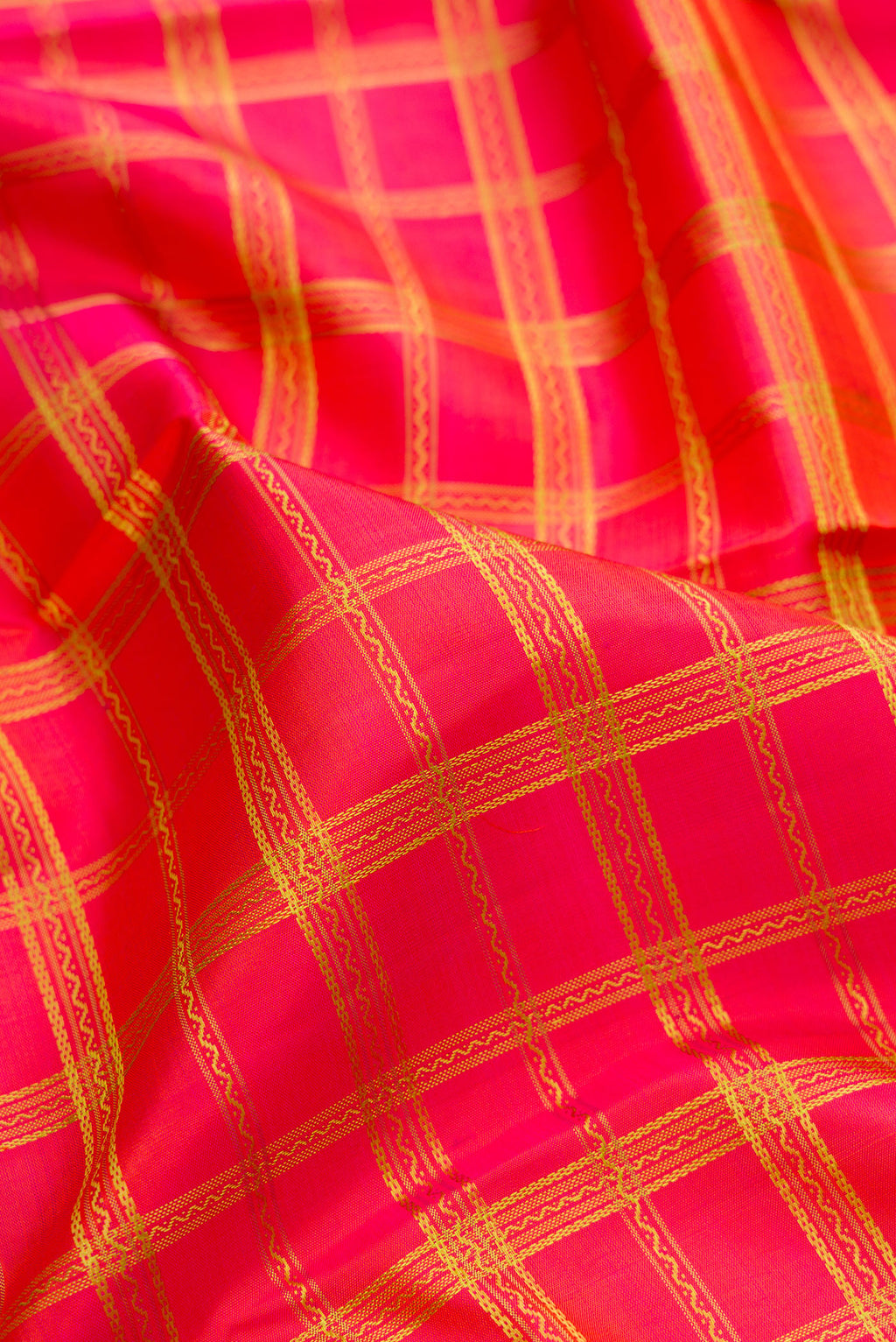 Close up of Pure Silk Pure Zari Coral Dual Tone Kanchipuram Saree with Checked design on the body and Zari And Thread Border.  displaying folds