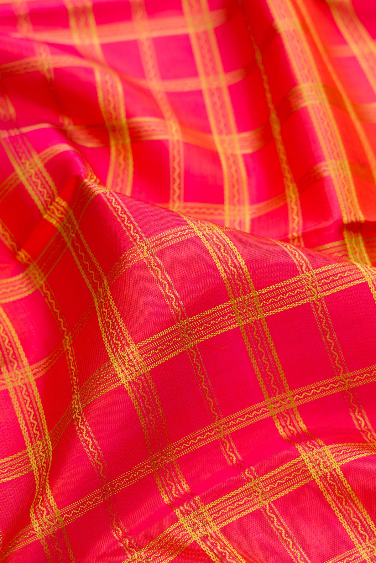 Close up of Pure Silk Pure Zari Coral Dual Tone Kanchipuram Saree with Checked design on the body and Zari And Thread Border.  displaying folds