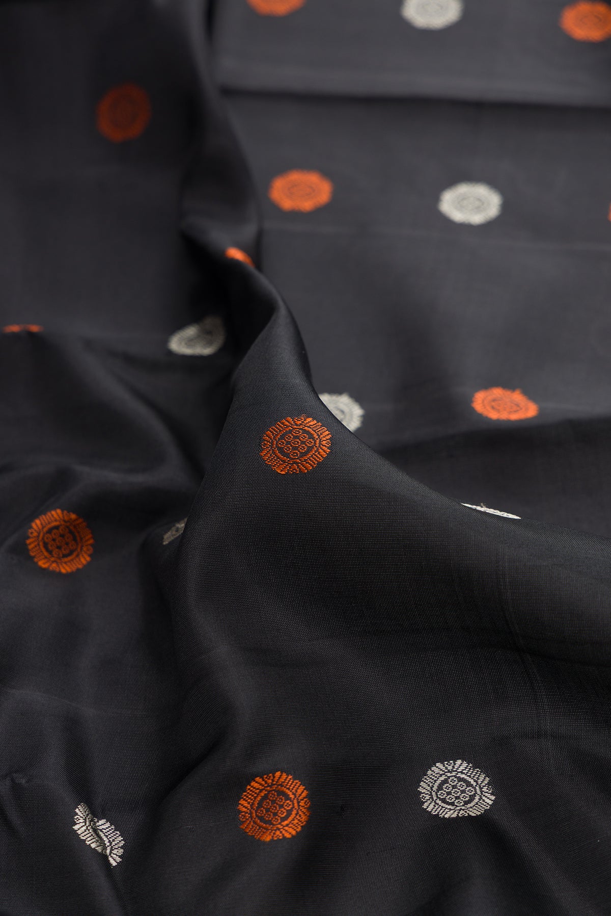 Close up of Pure Silk Black Kanjivaram Saree with Thread Butta on the body and Thread Border.  displaying folds