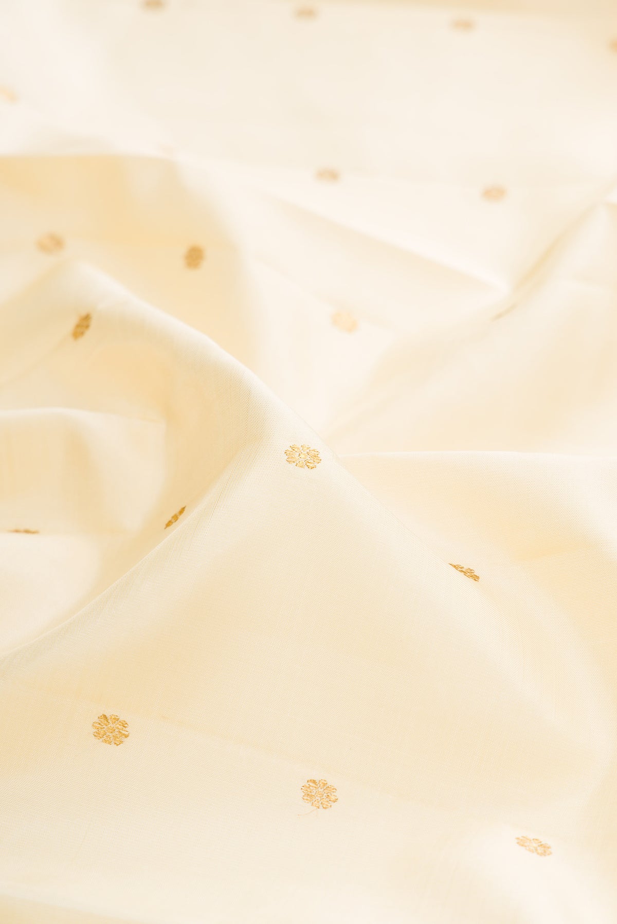 Close up of Pure Silk Pure Zari Cream Kanjivaram Saree with Zari Butta on the body and Zari Border.  displaying folds