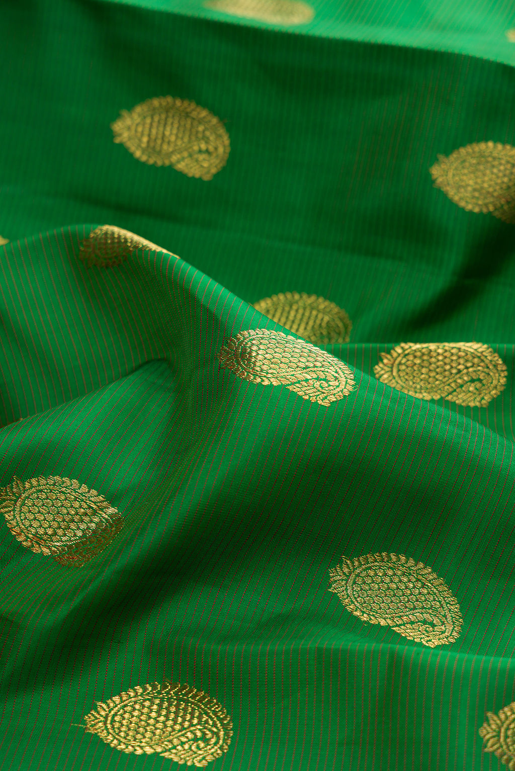 Close up of Pure Silk Pure Zari Green Kanjivaram Saree with Zari Butta on the body and Zari Border.  displaying folds