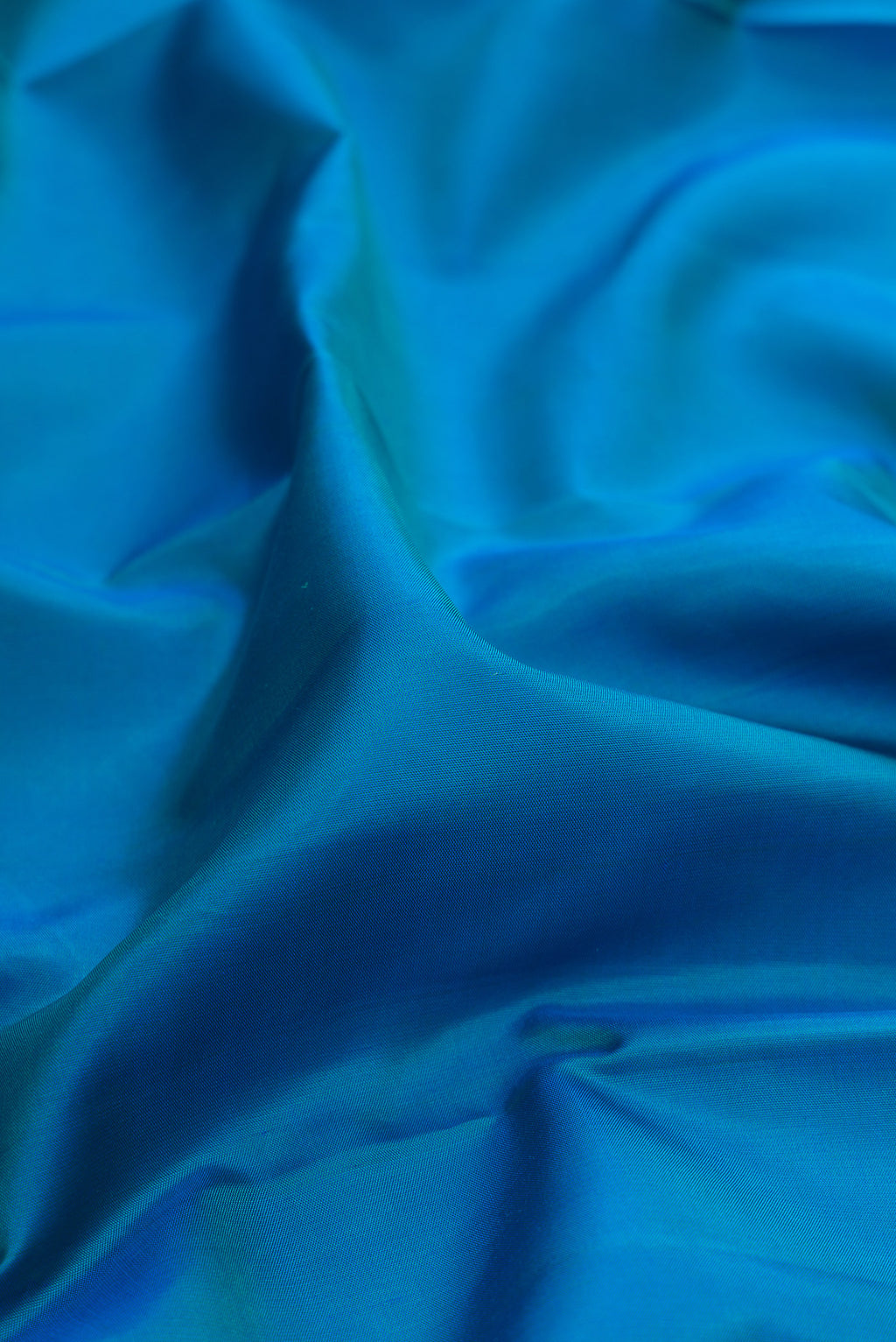 Close up of Pure Silk Peacock Blue Dual Tone Kanjivaram Saree with Plain Body and Plain Border.  displaying folds