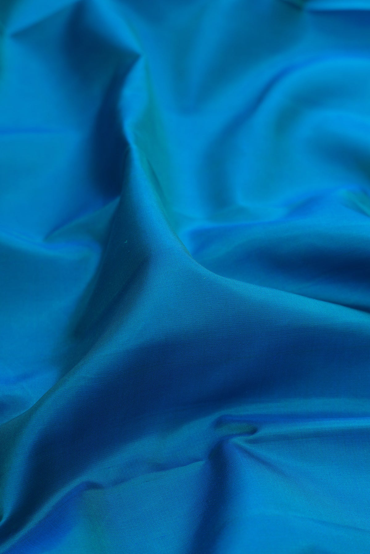 Close up of Pure Silk Peacock Blue Dual Tone Kanjivaram Saree with Plain Body and Plain Border.  displaying folds