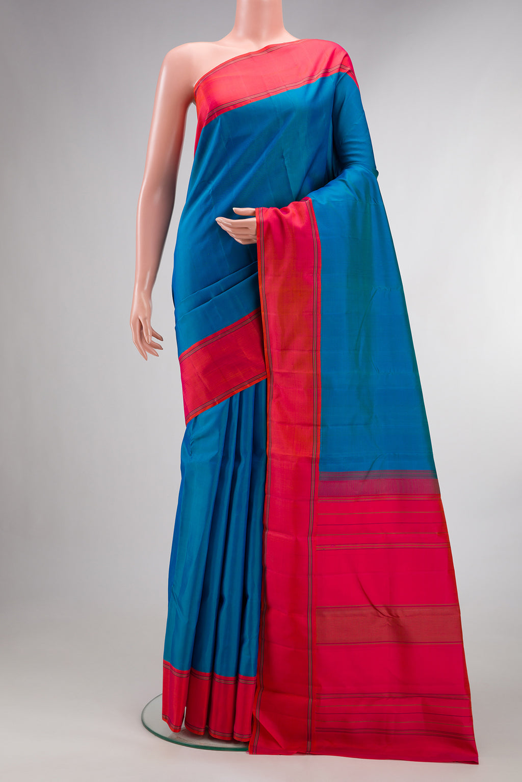 Pure Silk Peacock Blue Dual Tone Kanjivaram Saree with Plain Body and Plain Border.  displayed on a mannequin